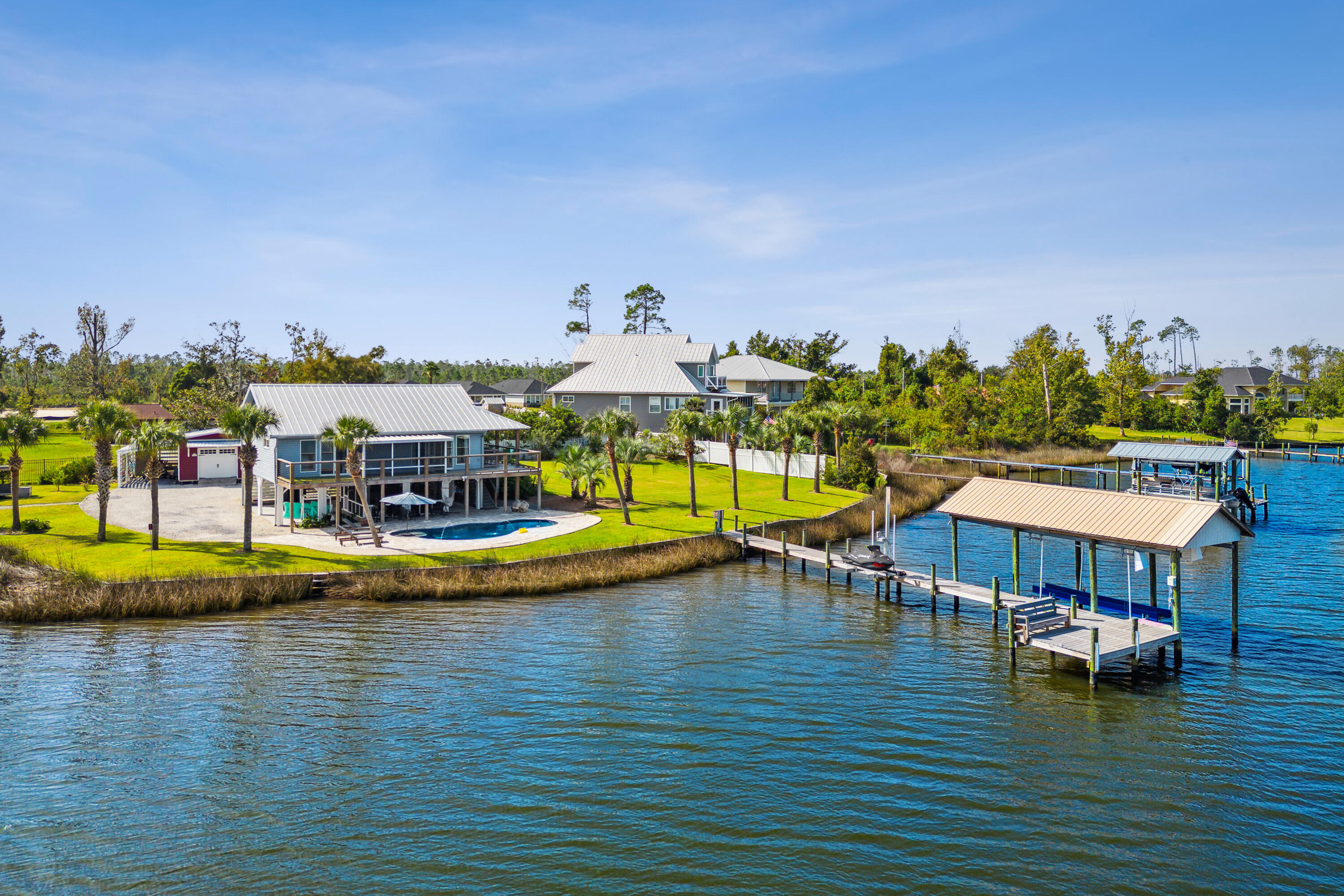 Gorgeous waterfront home that's as close to paradise as you can get. As you enter through your private security gate fresh beautiful landscaping abounds with breathtaking views of the deep waters of Cook Bayou and East Bay. Along with the views is your own private salt water pool that adds a spa like serenity to this little piece of paradise. Entering the home, you will immediately notice the bright open floor plan of the living room, kitchen and dining area. The soft wall colors, natural light and beautiful tongue in groove ceilings create a relaxing environment that makes this cozy home feel comfortable and inviting. Prepare your meals in the beautiful, as well as functional kitchen while admiring your waterfront view. The large primary bedroom has sliding glass doors that lead out to the balcony and screened in porch that overlooks the bay and pool. The primary bathroom will take your breath away with its spa like feel, with glass walls, double vanity, and tiled shower. On the way to the dock, you will find the recently added 12,000 gallon salt water heated pool with water feature and LED lights. Continue down the composite wood dock to find the covered boat lift with electric motors and a newly installed jet ski lift. Imagine ending your day relaxing on the custom-built bench at the end of the dock watching the dolphins play and birds feed as the sun sets and delivers an unimagined beauty. Every upgrade in this home was carefully thought out and designed for efficiency, functionality, and energy savings from the seamed metal roof to the Bosch air conditioning system. Large oversized work shop with electricity and a lean-to on both sides is great for the hobbyist or craft enthusiast. If you're looking for beautiful property that provides amazing access to water sports and some of the most stunning sunsets around, then you have found it.