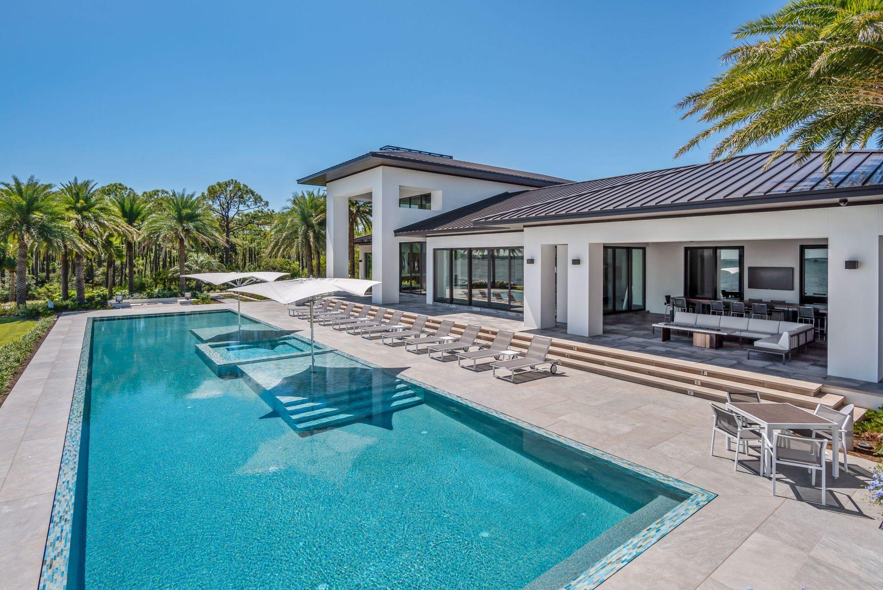 Progressively designed, and meticulously placed upon one of the single most premier parcels in Destin, Florida, this estate exemplifies waterfront luxury to the modern consumer. This 7,269 square foot George Small designed contemporary encapsulates crisp, modern styling both inside and out. Boasting a private dock, 88-foot perimeter overflow pool, 278 feet of water frontage, and a covered summer kitchen area, this one-of-a-kind property offers an ownership experience like none other. Upon entering this 2.53 acre estate, the custom laid Tecura Designs concrete paver driveway escorts visitors toward the oversized garage, and custom built pivot hinged steel French doors.