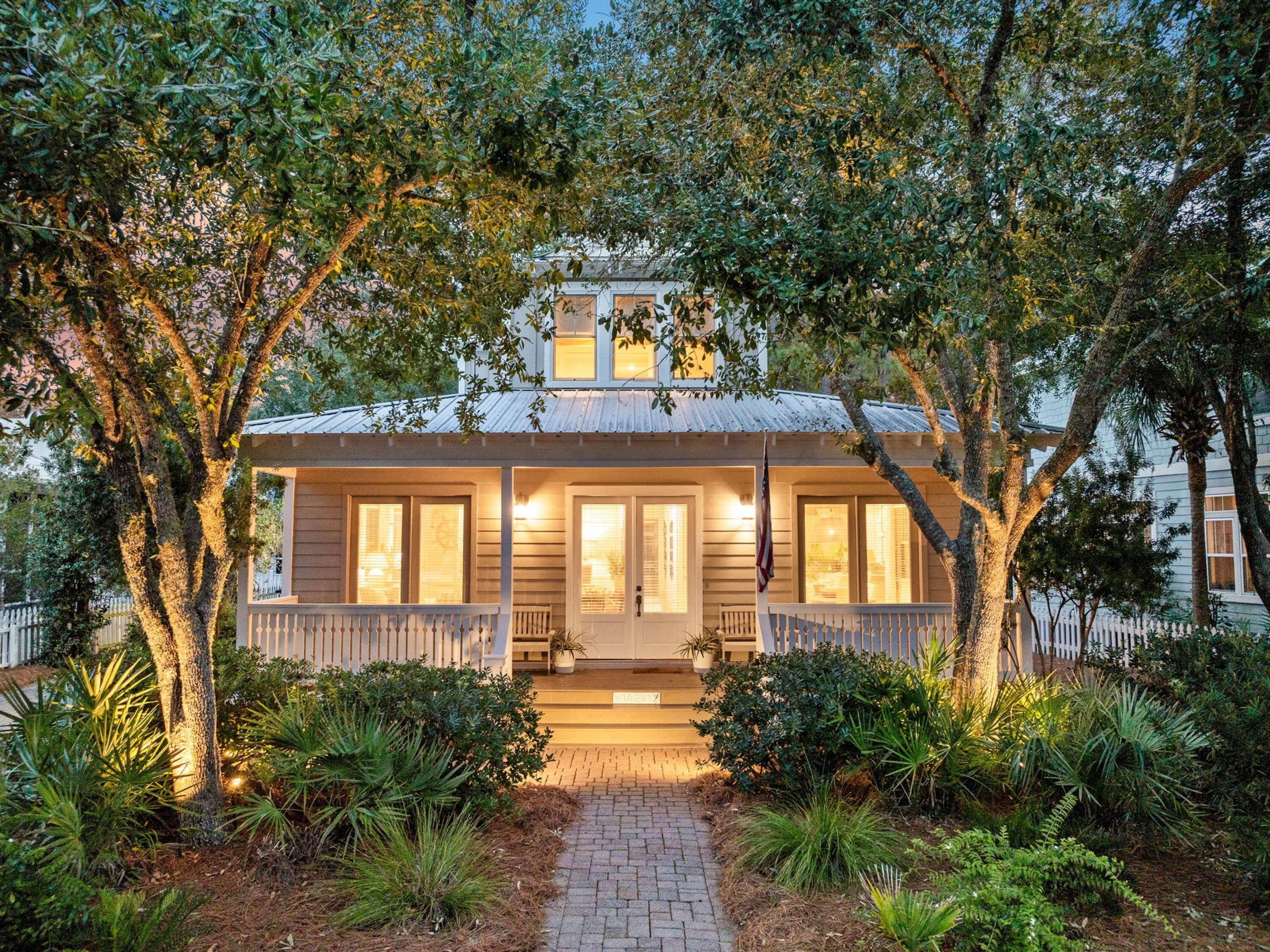 Enjoying beautiful coastal surroundings, this stylishly updated beach cottage is a real gem. A brick-paved path heads up to a welcoming full-width porch with multiple French doors leading into a spacious family room. Gleaming hardwood floors, airy 10-foot ceilings, and pristine shiplap combine to create a timeless ambiance in the spacious living room. Tasteful decor and multiple updates are enhanced by the comfortable new furnishings. An open kitchen invites cooks to be part of the conversation while preparing meals. Custom cabinets and high-end stainless steel appliances are supplemented with a pantry for organized storage. Hop onto one of the bar stools and enjoy social conversation over snacks and happy hour drinks. The nearby dining table comfortably seats eight when hosting family meals and entertaining. Follow the hallway past the laundry room and bedrooms to a generous screened porch. It looks out onto a natural landscape of mature fruit trees and a community conservation area of mature trees. Wood flooring and a swing seat make this an inviting space to read and relax in the fresh air. Three generously sized first-floor bedrooms include a primary suite with a beamed ceiling and two separate closets. The sleek master bathroom has a granite-topped twin vanity and an oversized shower with a frameless glass door. Two additional bedrooms share a well-appointed family bathroom and another ensuite. Upstairs, there's a second master bedroom with its own balcony for savoring peaceful moments overlooking the rear yard. A lavish ensuite bathroom elevates the spa-like experience. There's also a newly completed fifth bedroom on this level. Built-in bunks sleep four guests, providing youngsters with their own private hideaway. The real beauty of this immaculate beach house is the location, just five minutes walk from the beautiful sandy beach. Situated between popular Seaside, Florida, and Greenway Station, Cassine Village is a friendly coastal community with just 74 cottages sharing two pools, tennis courts, a fishing lake, fitness trails, a picnic area and deeded beach access. Off-road parking and a private barbecue area with a fire pit complete the excellent amenities at this peaceful retreat, which would make an ideal full-time residence or vacation retreat.