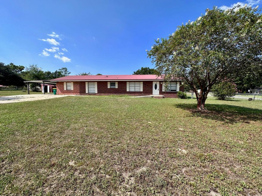 This spacious 4-bedroom, two-bathroom brick home sits on a full-acre corner lot in a convenient location near downtown Crestview. While it requires some renovation to restore its former glory, it promises ample room to create the perfect space for your large family. Inside, you'll find a large kitchen with a breakfast/dining area.  Additionally, there's a versatile bonus room that can be used as a den or office with an entry to the large Florida room on the back of the home. The home has a metal roof with a two car carport.