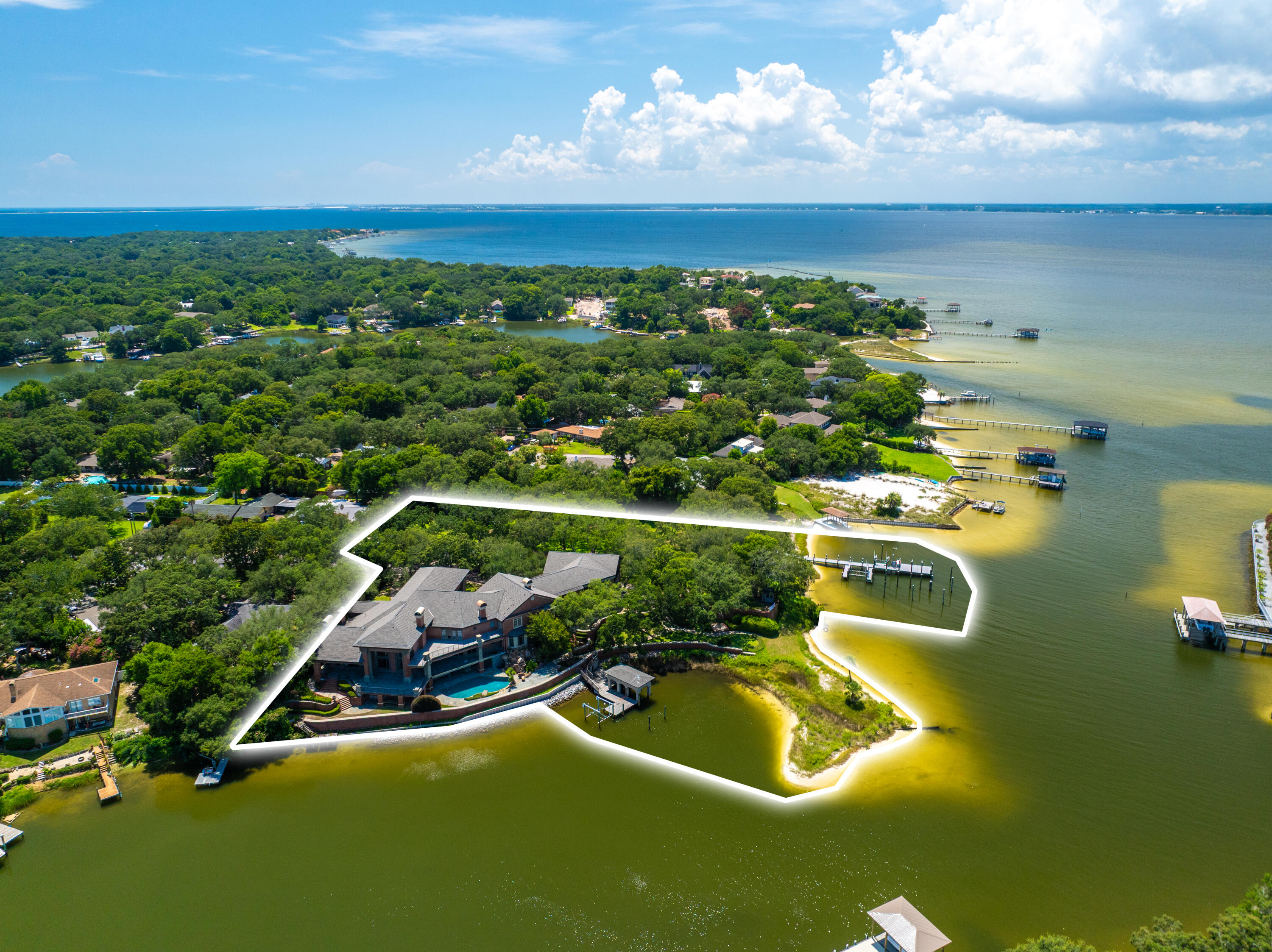 PREMIER WATERFRONT ESTATE - Nestled along 825 feet of pristine waterfront, this 14,203 sq ft estate is a grand architectural masterpiece, offering unparalleled panoramic views of the water. Featuring 2 direct deep-water dock accesses ideal for yachts, this residence is a refined retreat. Over 6,000 sq ft of expansive terraces invite alfresco dining and breathtaking sunset views. The resort-style pool, complemented by a state-of-the-art outdoor kitchen, offers the ultimate venue for grand entertaining. Set on 2.98 acres of meticulously manicured grounds, this private sanctuary combines regal design with timeless elegance. Experience the rare opportunity to own this extraordinary waterfront estate in Gulf Breeze, where unrivaled luxury, and refined sophistication converge.