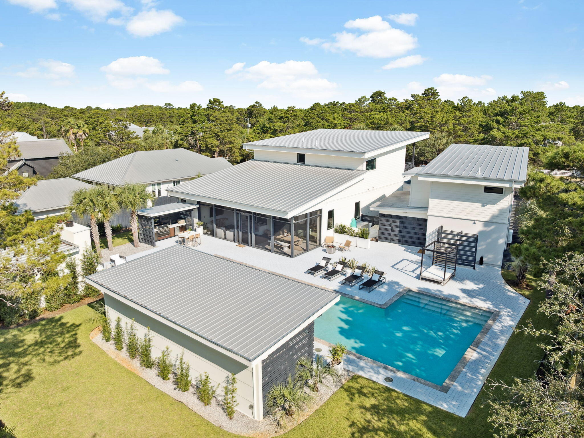 Welcome to an entertainer's dream home on a half-acre in The Pines of Blue Mountain Beach off Scenic Hwy 30A .This stunning contemporary home offers a true ''wow'' factor from the moment you arrive through the gated entrance. You'll be delighted by the open floor plan, where the kitchen, dining, and living areas seamlessly flow together, all featuring vaulted beamed ceilings, white oak floors, and unique lighting. A wall of windows leads to a screened porch with oversized lounging and dining arrangements. Just steps away, the outdoor entertaining space awaits with an outdoor kitchen and covered pavilion with lounge seating, television, a circular dining table and ping pong! Delight under the stars by the outdoor fireplace, with cozy chairs. Children will love bouncing on the in ground trampoline or spending time in the the two-story playhouse, which can also easily serve as a yoga/art studio or office space. Enjoy the generously oversized heated saltwater pool with an attached spa and sun shelf. The gourmet kitchen boasts high-end Thermador appliances, two dishwashers, a 6-burner convection dual-fuel range, and a nugget ice maker in the pantry. The first-floor primary suite offers simple elegance with a private covered porch and firepit lounging. The second level includes a junior suite with a balcony, an extra-large shower, and a walk-in closet, along with two guest bedrooms that share a bath.Separate living quarters are located above the second garage, providing additional space for guests with a full kitchen, living area, bedroom, and shower bath. The location is ideal, with Gulf Place just a 5-minute drive or a 10-minute bike ride away, providing access to numerous shops, restaurants, and the Ed Walline beach access. You can also easily reach Seaside via the bike path or Grand Boulevard with a quick 20-minute drive. This property offers versatility as a full-time residence, a vacation home, or an income-producing investment.