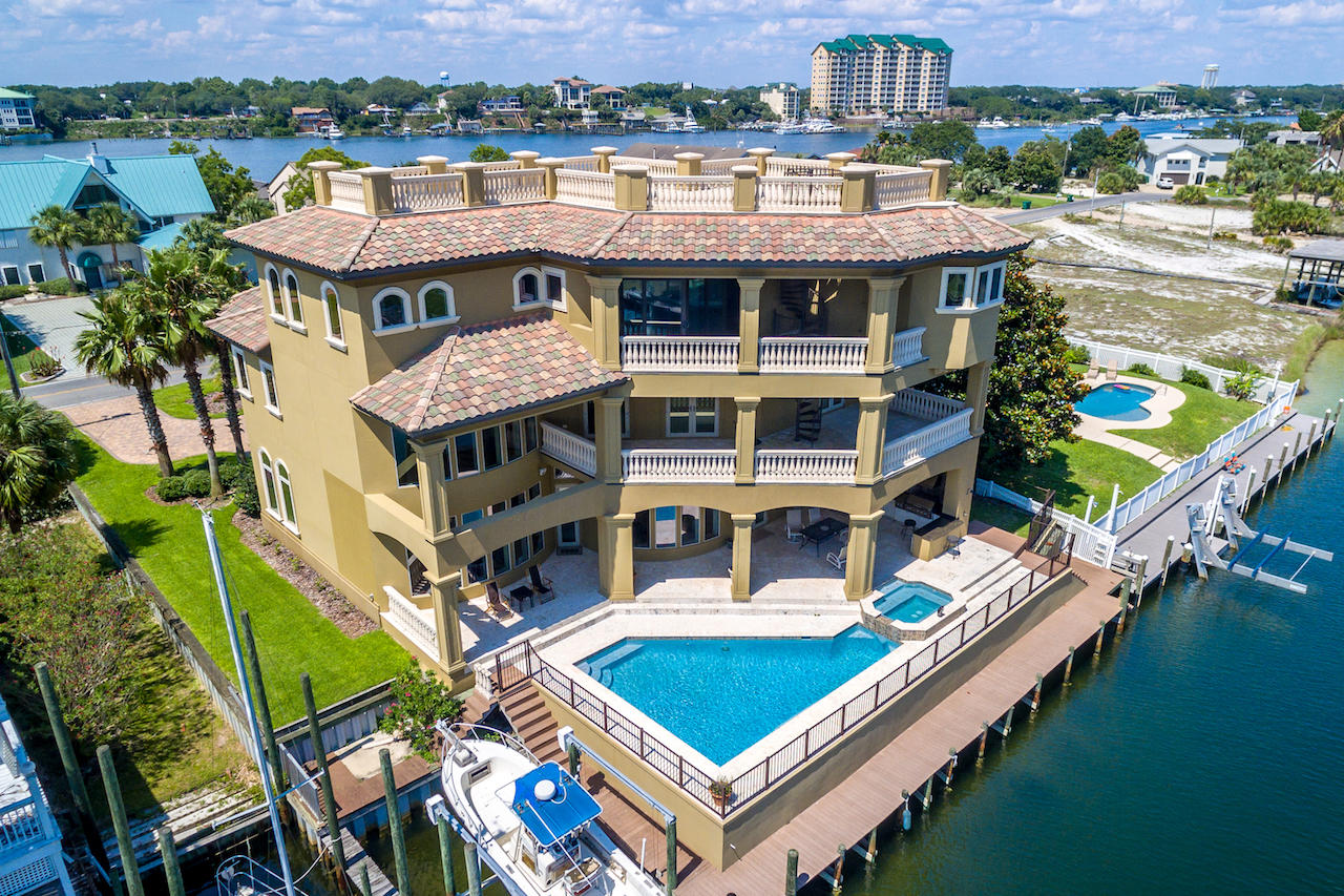 This custom-built, canal-front beauty is the perfect place to store your boat and enjoy the perks of living on the water in the heart of Destin. Watch the fireworks from multiple balconies and enjoy the 75ft dock and boatlift that accommodates up to a 30ft boat. The fabulous heated salt-water pool, hot tub and outdoor living area, complete with built-in grill and coral stone pavers, complement the outdoor lifestyle. As you walk through the custom wood doors, you are greeted by a double row of curved, canal-front windows extending the height of the 22ft ceiling. Imported Marbella shell stone adorns the floors, while painted coffered ceilings add architectural interest. The dramatic gas fireplace encased by built-in cabinetry and beautiful surround extending to the ceiling is a focal point. With cherry cabinets, beautiful granite counters and high-end appliances including a Wolf 6-burner range with double ovens, Bosch dishwasher, Fisher Paykel dishwasher drawer, wine cooler and Viking stainless refrigerator, large walk-in pantry, breakfast bar, and dining area, the chef's kitchen will delight the epicurean in your family. Also on the first floor, there is a formal dining room, a game room, a half bath and a laundry room with cabinets, a laundry shoot and an extra refrigerator. The beautiful curved stairway with iron railing leads to the second floor with three guest suites. There is also an office or den on this level. You will also enjoy Gulf views from the large second floor balconies. The third floor boasts a large master bedroom with sweeping views of the harbor and Gulf. The large master bath includes a jetted tub, large walk-through shower with double showerheads, and double vanities with unique Rainforest Brown granite. There are his and hers walk-in closets with custom cabinets and shelving. A morning coffee bar complete with a sink and refrigerator allows easy access for that first cup of coffee to be enjoyed on the balcony. Also on this level are other rooms that could be used for a hobby room, exercise room, office and bedrooms. The spiral staircase on the balcony leads to a rooftop deck with amazing views of the harbor, Gulf and East Pass. Additional custom features include an elevator, smart house wiring, Brazilian cherry hardwood floors on the second and third floors, faux finishes, generator wiring, three AC units and vessel sinks. The first level of the home is concrete block up to 12' and was built on 90 pilings. Take your boat to Crab Island, the Harbor or the Gulf and enjoy waterfront living at its finest.