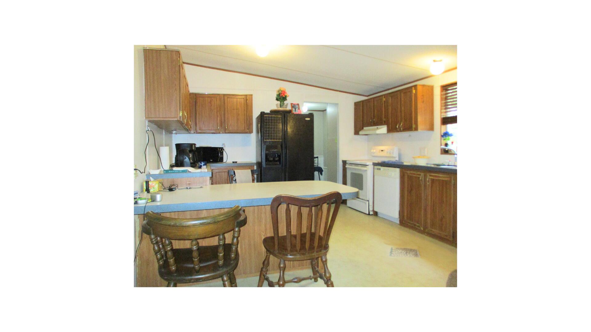 You CAN own a home. This double wide mobile sits on a fenced in, nearly 1/3 acre lot with mature oaks in the back yard. A newer, hurricane strapped metal roof protects this split floor plan home and covers the wide private front porch, and it has a ramp for gentle access. The open concept living room connects with the dining room and the generous kitchen. Steps away is the laundry room with a door to the expansive back yard. Enjoy privacy in your large primary bedroom, complete with a walk-in closet, and an ensuite with soaking tub and separate shower. Two additional bedrooms reside off the living room and share the other full bathroom. Tinker in your separate garage/workshop with electricity and loft storage. Don't miss out on your chance to purchase this home and make it your own! From Ferris Drive this double wide mobile home property has a raised, higher-than-street level, open front yard with a full-frontal view of the trailer home. The view looking over the trailer roof in the background is a tree grove of Southern Live Oak. The trailer front faces West and the back faces East, which is perfect for enjoying sunsets and sunrises. The front windows have shutters. The 22ft wide 2-car driveway is grey permeable, environmental-friendly, crushed pea gravel. The trailer home entrance is a 14ft ramp to an 8ft x 18ft roofed porch enclosed with 4ft high white lattice fencing giving a private view of evening sunsets.
The front door enters to an open floor plan that opens the living room to the dining room and to the kitchen with vaulted ceilings. The living room gives access to the master bedroom/bathroom on the Northside of the trailer home. The living room, dining room and kitchen ceilings are 7 1/2ft x 9ft pitched ceilings with
ceiling fans in the living & dining rooms. The living room's picture windows look to the West onto the front porch and Ferris Drive and evening sunsets. The low pile, soft-underfoot, beige, SD polyester fiber carpeting in the living and dining rooms and the master bedroom was installed in 2023.
The master bedroom is a roomy 17ft x 13ft with a ceiling fan and a 5 1/2ft x 7 1/2ft walk-in closet. The master bedroom picture
windows face the West and look onto the front yard and street. The master bathroom has extra floor space with bright over-the-sink and ceiling lighting, extra cabinets 2 extra-large wall mirrors, shower stall and an extra-large soaking bath tub (55"x 35" x 18") surrounded by a 19" platform. The dining room is open to the kitchen with a 4ft x 3ft dining countertop separating the 2 rooms. The kitchen cabinetry is wall-mounted and under-the-counters installed. The kitchen window looks into the backyard and to the East. Adjacent to the kitchen is the mud room with washer and dryer; it also houses the 30gal capacity water heater, electricity circuit breaker box and the A/C air handler cabinet. The mud room back door opens onto a small deck and backyard. The small deck and backyard are illuminated by 2 lamp flood light fixture. The 72ft x 72ft backyard is an open space playground / park land / bird land fully fenced and populated with a dozen Southern Live Oak trees. A red-headed woodpecker has re-purposed a limb on one of the trees into 5 birdnest condos. In addition to the trees the backyard has a 12ft x 12ft covered lanai, a 10ft x 13ft x 7
1/2ft pitched roof metal storage shed placed on a concrete pad and a 6ft x 8ft x 7ft pitched roof metal storage shed placed on concrete foot pads. This shed has shelving and a shop light.
Behind the backyard fence is a 200yd wide multi-utility easement. The benefit of this easement is that it's a peaceful space, no traffic or backyard neighbors.
The trailer home's front and backyards are easy to maintain. The HNWS utility service water meter box is in the Northwest corner of the front yard next to the street light utility pole. The FPL electricity utility service meter is located on a utility post in the Northeast corner of the backyard. There is one (1) outdoor
water bib; it is in the front yard under the master bedroom picture windows. There are about 200' of used garden hoses provided with the property. A Honda/Toro self-propelled lawnmower is also provided with the property garage. Yard waste and house garbage is collected weekly on Tuesday & Wednesday mornings respectively by Waste-Pro USA. Between the south side of the trailer home and the garage is a 10ft wide x 23ft long concrete patio. The front of the patio is secured by 9ft wide x 5 1/2ft high swinging padlocked cyclone chain link fence. The patio is illuminated by a motion
sensor lighting fixture. The garage / workshop was installed in 2019. It is a fully enclosed 14ft x 23ft x 9ft vertical roof with a standard pitch metal building with a side door &
window and an 8ft X 9ft rollup front door. The garage has a LED shop light, a roomy loft, 14' x 6' metal shelving on one side of garage and 7' x 6' of shelving on the other side.
Hidden Creek Golf Club is only 1mile away.