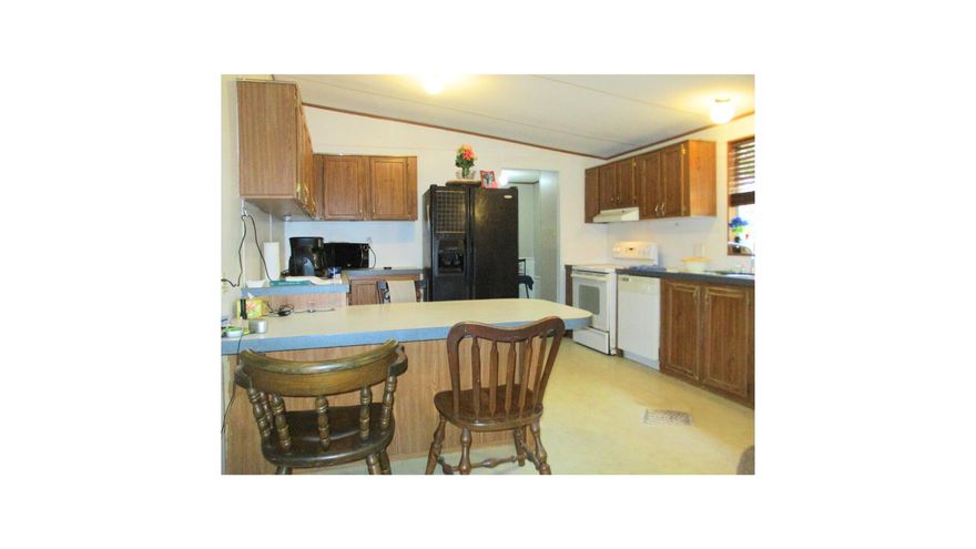 You CAN own a home. This double wide mobile sits on a fenced in, nearly 1/3 acre lot with mature oaks in the back yard. A newer, hurricane strapped metal roof protects this split floor plan home and covers the wide private front porch, and it has a ramp for gentle access. The open concept living room connects with the dining room and the generous kitchen. Steps away is the laundry room with a door to the expansive back yard.  Enjoy privacy in your large primary bedroom, complete with a walk-in closet, and an ensuite with soaking tub and separate shower. Two additional bedrooms reside off the living room and share the other full bathroom. Tinker in your separate garage/workshop with electricity and loft storage. Don't miss out on your chance to purchase this home and make it your own! From Ferris Drive this double wide mobile home property has a raised, higher-than-street level, open front yard with a full-frontal view of the trailer home. The view looking over the trailer roof in the background is a tree grove of Southern Live Oak. The trailer front faces West and the back faces East, which is perfect for enjoying sunsets and sunrises. The front windows have shutters. The 22ft wide 2-car driveway is grey permeable, environmental-friendly, crushed pea gravel. The trailer home entrance is a 14ft ramp to an 8ft x 18ft roofed porch enclosed with 4ft high white lattice fencing giving a private view of evening sunsets.
The front door enters to an open floor plan that opens the living room to the dining room and to the kitchen with vaulted ceilings. The living room gives access to the master bedroom/bathroom on the Northside of the trailer home. The living room, dining room and kitchen ceilings are 7 1/2ft x 9ft pitched ceilings with
ceiling fans in the living & dining rooms. The living room's picture windows look to the West onto the front porch and Ferris Drive and evening sunsets. The low pile, soft-underfoot, beige, SD polyester fiber carpeting in the living and dining rooms and the master bedroom was installed in 2023.
The master bedroom is a roomy 17ft x 13ft with a ceiling fan and a 5 1/2ft x 7 1/2ft walk-in closet. The master bedroom picture
windows face the West and look onto the front yard and street. The master bathroom has extra floor space with bright over-the-sink and ceiling lighting, extra cabinets 2 extra-large wall mirrors, shower stall and an extra-large soaking bath tub (55"x 35" x 18") surrounded by a 19" platform. The dining room is open to the kitchen with a 4ft x 3ft dining countertop separating the 2 rooms. The kitchen cabinetry is wall-mounted and under-the-counters installed. The kitchen window looks into the backyard and to the East. Adjacent to the kitchen is the mud room with washer and dryer; it also houses the 30gal capacity water heater, electricity circuit breaker box and the A/C air handler cabinet. The mud room back door opens onto a small deck and backyard. The small deck and backyard are illuminated by 2 lamp flood light fixture. The 72ft x 72ft backyard is an open space playground / park land / bird land fully fenced and populated with a dozen Southern Live Oak trees. A red-headed woodpecker has re-purposed a limb on one of the trees into 5 birdnest condos. In addition to the trees the backyard has a 12ft x 12ft covered lanai, a 10ft x 13ft x 7
1/2ft pitched roof metal storage shed placed on a concrete pad and a 6ft x 8ft x 7ft pitched roof metal storage shed placed on concrete foot pads. This shed has shelving and a shop light.
Behind the backyard fence is a 200yd wide multi-utility easement. The benefit of this easement is that it's a peaceful space, no traffic or backyard neighbors.
The trailer home's front and backyards are easy to maintain. The HNWS utility service water meter box is in the Northwest corner of the front yard next to the street light utility pole. The FPL electricity utility service meter is located on a utility post in the Northeast corner of the backyard. There is one (1) outdoor
water bib; it is in the front yard under the master bedroom picture windows. There are about 200' of used garden hoses provided with the property. A Honda/Toro self-propelled lawnmower is also provided with the property garage. Yard waste and house garbage is collected weekly on Tuesday & Wednesday mornings respectively by Waste-Pro USA. Between the south side of the trailer home and the garage is a 10ft wide x 23ft long concrete patio. The front of the patio is secured by 9ft wide x 5 1/2ft high swinging padlocked cyclone chain link fence. The patio is illuminated by a motion
sensor lighting fixture. The garage / workshop was installed in 2019. It is a fully enclosed 14ft x 23ft x 9ft vertical roof with a standard pitch metal building with a side door &
window and an 8ft X 9ft rollup front door. The garage has a LED shop light, a roomy loft, 14' x 6' metal shelving on one side of garage and 7' x 6' of shelving on the other side.
Hidden Creek Golf Club is only 1mile away.
