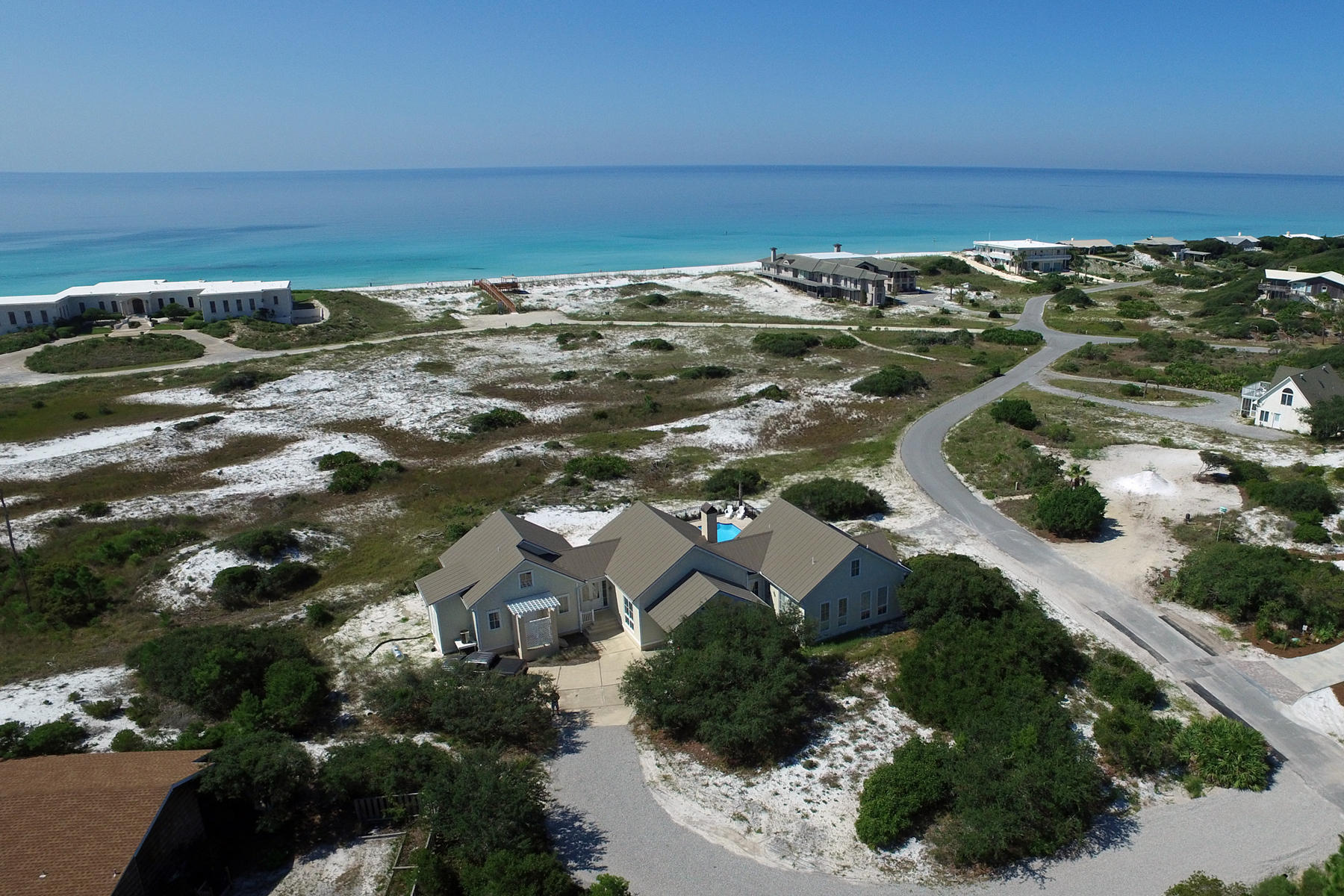 A beautiful home located in the uniquely private, gated historic community of Four Mile Village. This single-level living home is specially situated behind an expansive natural dunescape preserved by the Coffeen Land Trust that affords protected, panoramic views of the Gulf. This home centers around an enormous great room with cathedral ceiling trussed by natural timber beams, whose south-facing wall of windows frames a seaward view over natural dunes laced with scrub oaks and palmetto. Double pocket doors off the main entry foyer can be sealed to partition the master suite from the rest of the home, creating a private front entrance and access to the back porch and full-size in-ground pool.