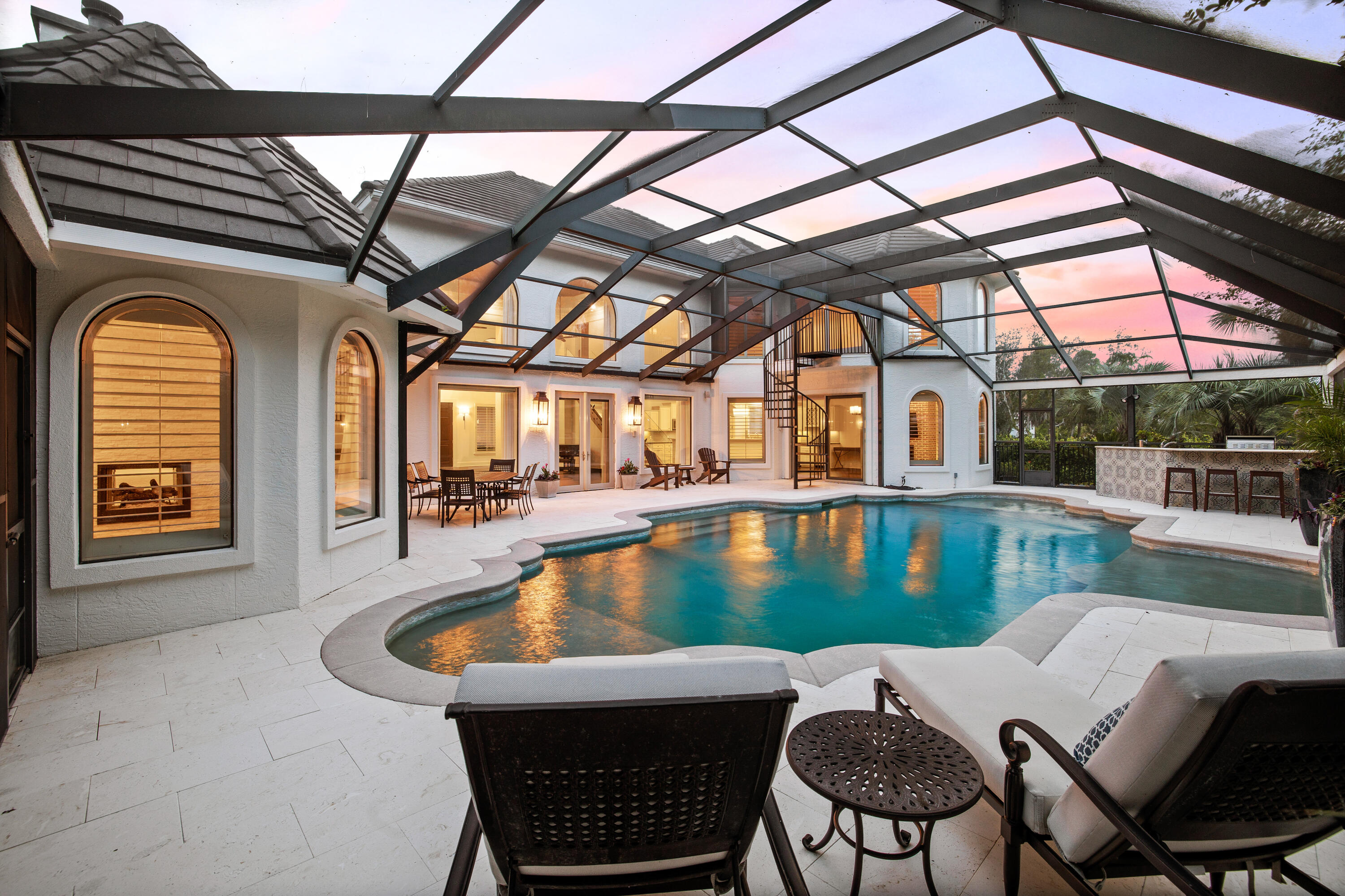 Tucked inside of the gated community of Regatta Bay sits this renovated waterfront Spanish-style estate. This stunning residence is perfectly positioned on the lake and just a short stroll from the bay. Upon entry, you are greeted by the spacious living room with 22' ceilings, a beautiful brick fireplace, and floor-to-ceiling windows flooding the room with natural light. the open floor plan allows for seamless entertaining and connects the living room to the kitchen and dining area. The chef's kitchen features dual ovens, a gas stove, oversized island, dual sinks, and a wet bar with an ice maker and wine cooler. The dining room showcases a brick fireplace and views of the stunning outdoor living area.