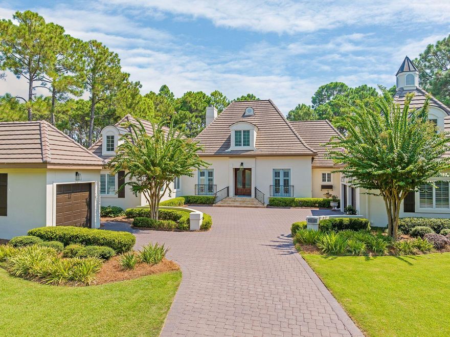 Nestled in mature pine trees and overlooking the Burnt Pine Golf Course, this magnificent estate offers 4,810 square feet of carefully maintained living space along with a three-car garage and a heated pool within a screened lanai. From the sweeping driveway, the French chateau-style architecture delivers jaw-dropping curb appeal. Steep gabled roofs punctuated by dormer windows add to the sense of grandeur. A light and airy foyer welcomes you inside, with three sets of double doors drawing you toward the shimmering waters of the outdoor pool. Pass through the formal dining room with lighted display cabinets and check out the sitting room with a feature fireplace with custom mantel creating a natural focal point. Textured walls, wood floors, Venetian plaster, barrel and beam ceilings and