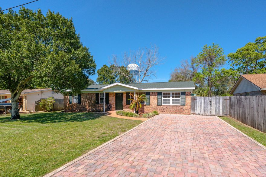 A paver driveway and front walk compliment the stately brick exterior on the front of the home.  The interior has new carpet and fresh paint throughout.  The living area and den at the front of the home have new ceiling fans.  Built-in bookcases frame one side of the entryway to the tiled kitchen and dining area.  The kitchen is complete with a double basin sink, pantry, new dishwasher, new refrigerator (2021), and breakfast bar. The rear of the home has sliding-glass door access to the privacy-fenced backyard and covered patio. Off of the dining area is a large laundry room.  On the left side of the home is a hallway with access to the bedrooms and full shared bath.  Past the first two bedrooms, complete with ceiling fans, is the primary bedroom featuring a half bath.