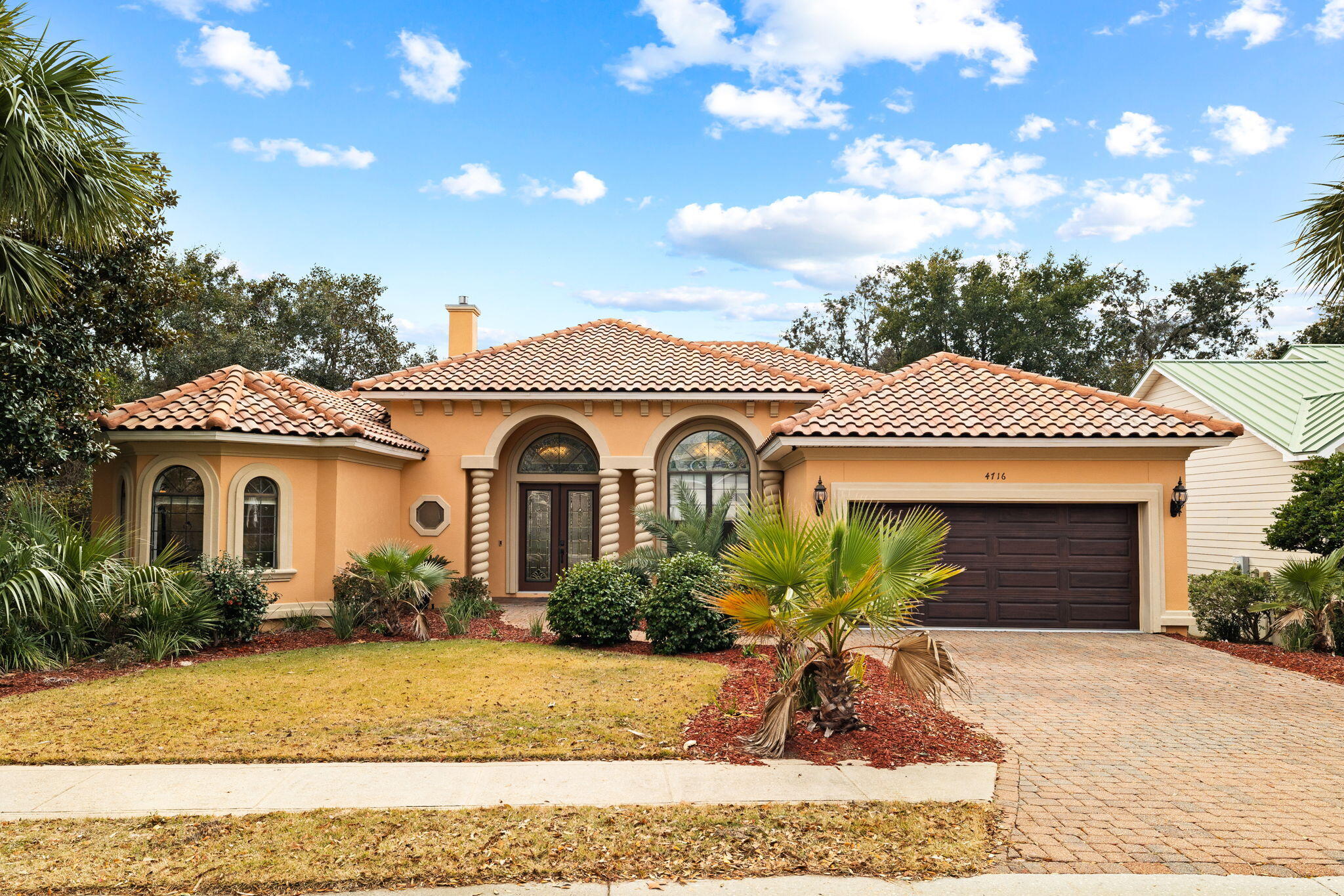 Upscale and impeccably maintained, this single level Mediterranean-inspired home is situated in the sought-after gated community of Destiny East. Characterized by an expansive and efficient footprint with intricate details from soaring 12' ceilings with stacked crown molding to tile and wood floors, this custom-built home offers a desirable floorplan for personal use or as a vacation rental. Ample living space with ornate millwork, niches, and a finely appointed finish level is highlighted by the formal dining area, a large kitchen with detailed cabinetry and breakfast bar, and 2 living room areas with a sitting area overlooking the pool in the backyard. Offered fully furnished with pieces selected by a local designer, the split-bedroom design offers privacy with the master suite standing alone on the left side of the floorplan. Desirable touches include a fireplace in the master bedroom, a trayed ceiling with lighting and ensuite master bath with separate vanities, soaking whirlpool tub and separate steam shower. 2 walk-in closets flank the arched-hallway leading into the master bath. Directly adjacent to the second living area is the guest suite with 2 guest bedrooms and a shared bath, and a walk-through laundry room from the kitchen leads to the 2-car garage, which houses an emergency generator. Large windows with stained glass casing the main living and dining areas allow natural light to flow through for an open and inviting feel. Two large sliding glass doors from both living spaces empty out onto the oversized covered porch that wraps around the heated pool and spa, with the entire area screened in and ready for entertaining.