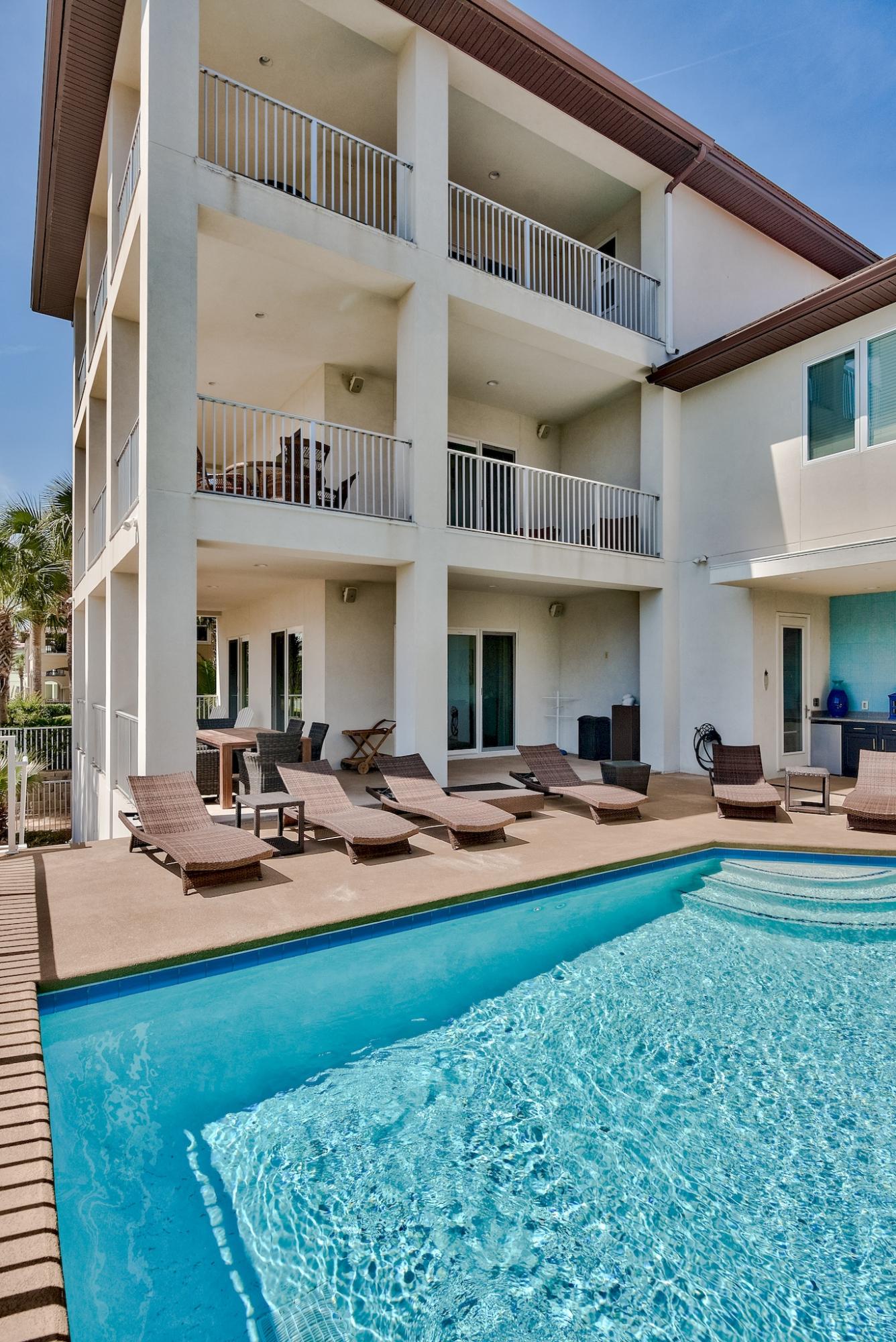 Gulf views from all 3 balconies! Turnkey home conveys fully furnished. Featuring 10 foot ceilings throughout. The entry level family room has a fireplace, foosball table, and dartboard for your entertainment. Directly outside is the elevated 1100 square foot grand pool deck, complete with a summer kitchen, grilling area, surround sound system, shower and a half bath. The entry floor also has a kitchenette/laundry room to accommodate guests staying in the two downstairs bedrooms, both of which have private baths. The larger bedroom contains two custom built queen beds, each topped with a full-sized bunk. Two owners closets plus additional storage are on the first floor as well. Take the stairs or the elevator