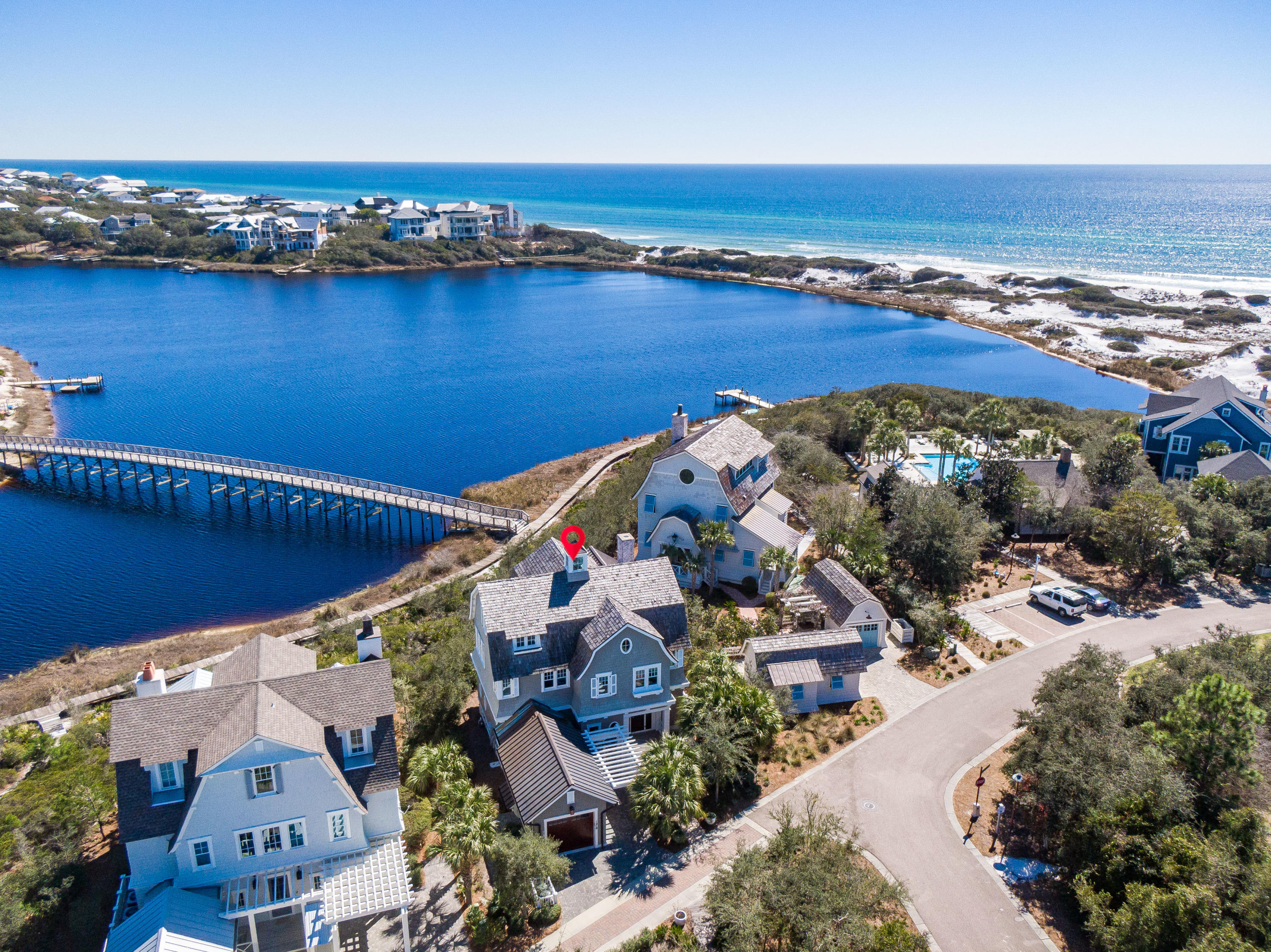 Perfectly situated along the shores of Camp Creek Lake, this magnificent residence is defined by classic maritime architecture and spectacular lake & Gulf views. Designed by T.S. Adams Studio Architects with decor & finishes by Erika Powell of Urban Grace Interiors, discover warm welcoming spaces highlighted by beautiful wood floors, coastal-style lighting, shiplap walls & exposed beams. Abundant natural light shines into the open second level living & dining areas with picturesque views out every window. A cozy double-sided gas fireplace centers the space with a sitting room on one side & the living area on the other.  Highlights of the gourmet kitchen include a large center island, commercial-grade Viking appliances, wine refrigerator, two beverage drawers, ice maker and