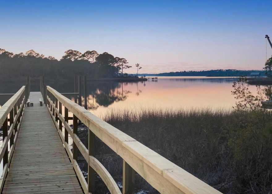 When luxurious style, practical function and respectful design are in harmony together, a home realizes its full potential. Place that home in the magical setting across from the area's largest rare Coastal Dune lake, Lake Powell, and an awe-inspiring oasis is created. This amazing property features a spectacular 2,860 square-foot luxury residence and private community dock. To step into the home is to cross over into a peaceful sanctuary. A well-designed floor plan creates a home to live easily, as well as entertain either intimate or family gatherings.  The main great room is truly grand, but offers cozy spaces for quiet conversation, filled with natural light from an abundance of windows.