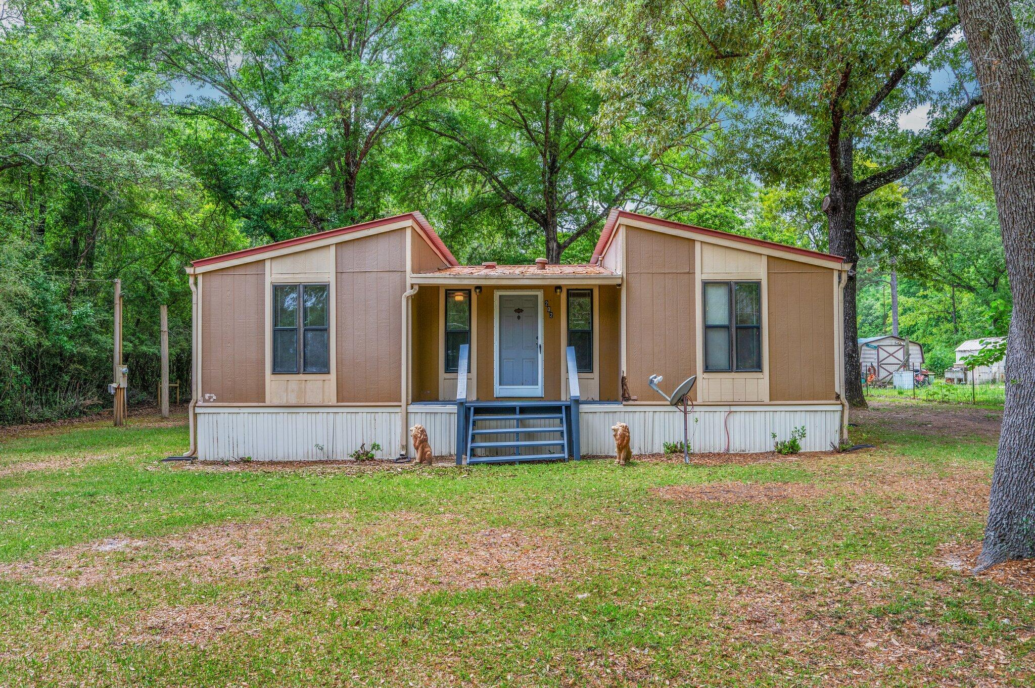 Opportunity awaits with this 1986 triple-wide mobile home offering 1,344 sq ft of living space and water view of Holly Lake. Set on a fully fenced one-acre lot, this property features 3 bedrooms, 2 full baths, and a bonus room with a cozy wood-burning fireplace--perfect for a relaxing retreat or weekend getaway. Outdoor living is a highlight here, with a screened-in porch, large open deck, and ample space to enjoy the peaceful surroundings. The home is serviced by city water, while a 230 ft submersible well supplies all exterior spigots--ideal for gardening or outdoor use. Additional features include: RV hookup with water, power, and septic connection. Workshop with power, water, & washer/dryer hookups. Additional yard building for storage. Carport for covered parking. With a little TLC, this property has great potential as a fishing camp, weekend escape, or full-time residence. Please note: Due to its current condition, this home will not qualify for traditional financing. Cash offers only.
