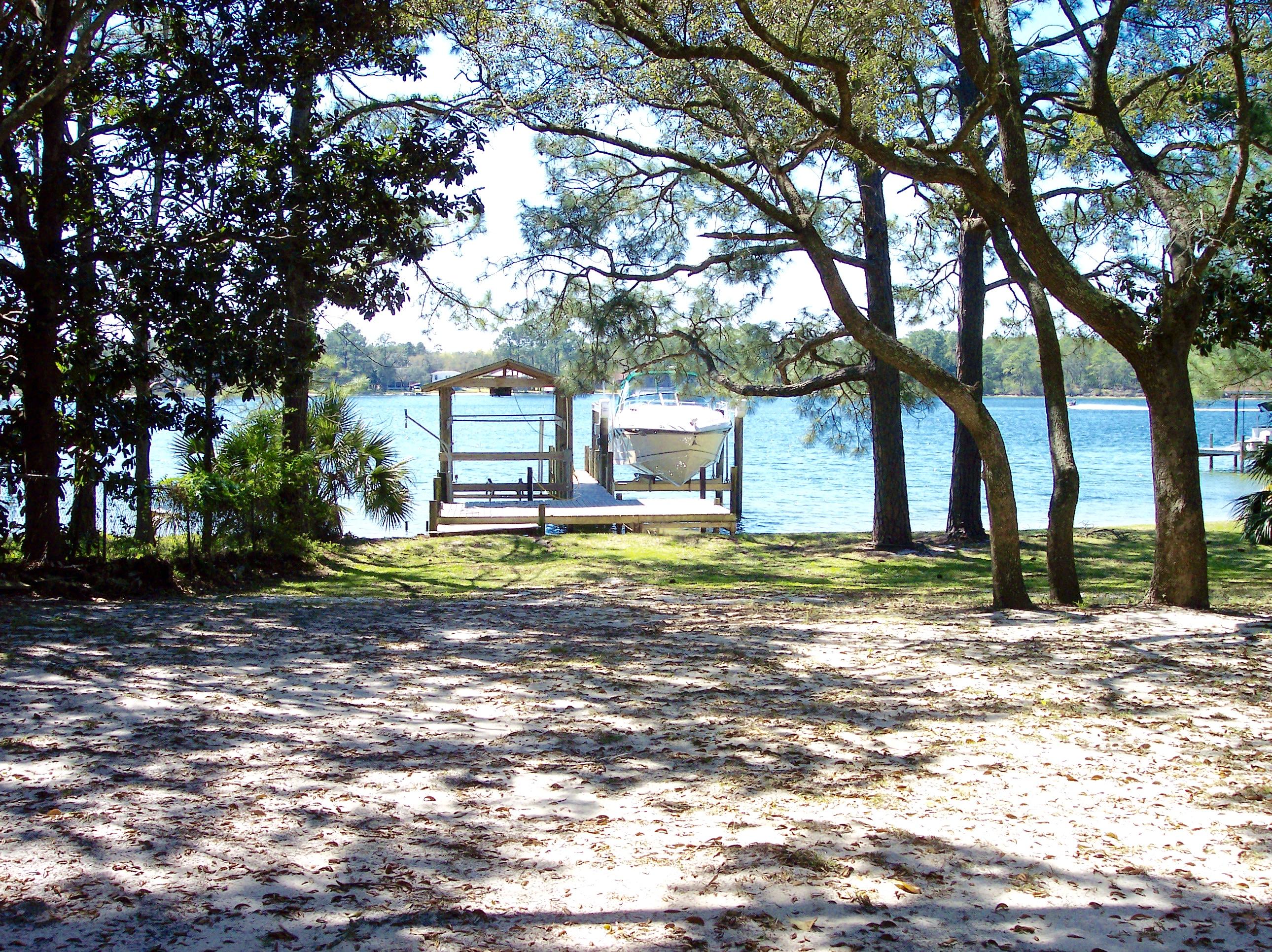 Poquito Bayou is now offering a chance for someone to own a waterfront home and boat house in the heart of the community. Opportunities like this don't come often, so make an appointment to view this property. The mid-century home was built and lived in by one owner since 1959. It is a jewel that needs some TLC, or start over and rebuild a new home. The lot has mature trees throughout and slopes down to the 75 Feet of waterfront paradise. The two boat lifts, dock, and boathouse (added in 1994) are yours for the taking. The house sits in the middle of the lot and has an attached carport big enough for two cars. The living space is an open mid-century floor plan. With some imagination this home could be renovated to accommodate any person's needs.