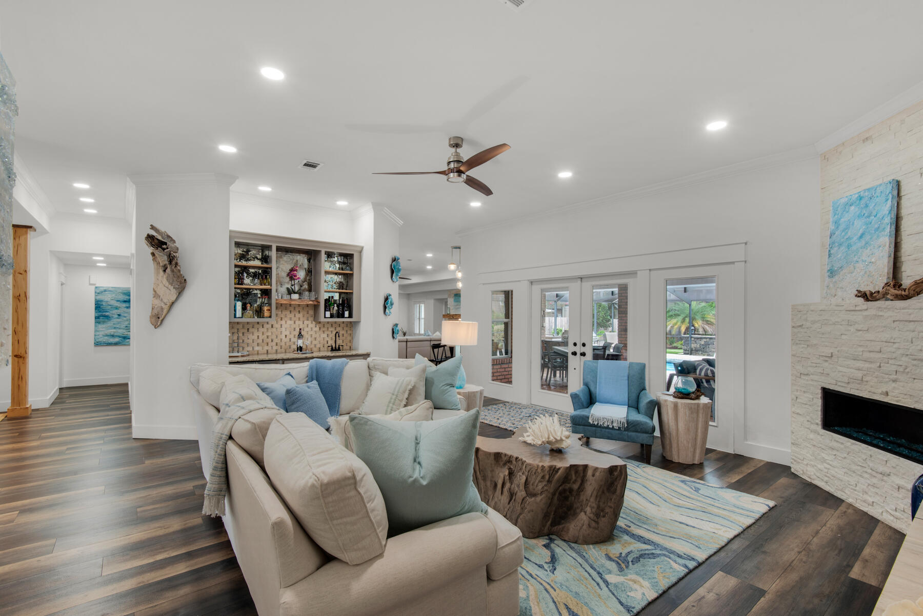 Located in a Gated Golf Course Community on the Bay. This home beautifully blends the comforts of modern living with timeless elegance. It's a seamless fusion of contemporary convenience and classic sophistication, creating a space that's not only stylish but also highly functional for today's lifestyle. The large 6' deep pool has also been upgraded to include full outdoor kitchen, new pavers, resurfacing, salt water filter and new heater. The house has undergone a remarkable transformation, guided by professional design expertise and a commitment to a modern coastal aesthetic that seamlessly integrates both its interior and exterior spaces. Every corner of the house has been touched by the complete remodel, new exterior Paint, completed new kitchen , fireplaces, bathrooms, bedrooms, lighting, floors, closets, new Bosh Coastal AC, Upon entering, a warm and inviting foyer ushers you into an expansive and open floor plan. Two distinct living rooms welcome you
with the formal living room featuring a fireplace and a well-appointed wet bar complete with a sink, wine and beverage cooler, and custom cypress shelf accents. The formal dining room exudes elegance with hand-hewn cypress columns, a trayed ceiling, and a dazzling chandelier. The kitchen, with its new layout, boasts quartz countertops, a glass backsplash, and brand-new cabinets offering additional storage. It's equipped with modern conveniences, including double ovens and stainless steel appliances. Gas fireplaces in both living rooms contribute to the cozy atmosphere, and custom touches such as plantation shutters, built-in bookcases, and step ceilings give the home its unique and welcoming character.
French doors in both living rooms lead to a covered outdoor living space, complete with a TV and dining area, as well as an outdoor kitchen with bar seating. This outdoor oasis overlooks the inviting pool, which has been recently resurfaced. Whether you're in the heated pool or relaxing in the outdoor living area, you can enjoy watching your favorite games on the large outdoor TV.
The main suite is a private sanctuary, occupying its own wing of the house. It features a luxurious bathroom with a walk-in shower and a soothing whirlpool tub, along with a custom-designed walk-in closet. A private guest wing offers pool access and an en-suite bathroom for added convenience.