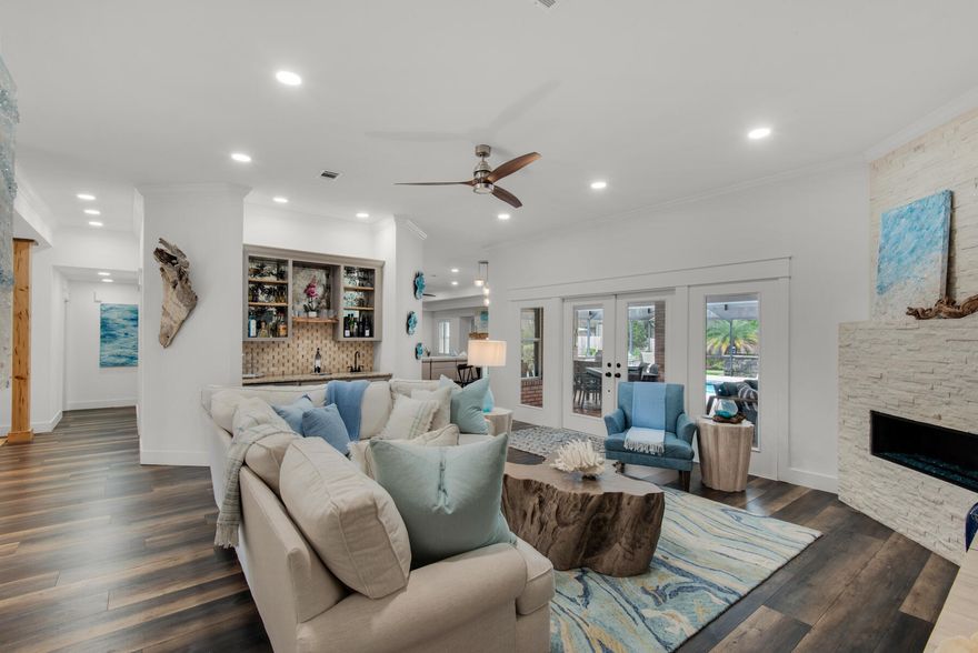 Located in a Gated Golf Course Community on the Bay. This home beautifully blends the comforts of modern living with timeless elegance. It's a seamless fusion of contemporary convenience and classic sophistication, creating a space that's not only stylish but also highly functional for today's lifestyle. The large 6' deep pool has also been upgraded to include full outdoor kitchen, new pavers, resurfacing, salt water filter and new heater. The house has undergone a remarkable transformation, guided by professional design expertise and a commitment to a modern coastal aesthetic that seamlessly integrates both its interior and exterior spaces. Every corner of the house has been touched by the complete remodel, new exterior Paint, completed new kitchen , fireplaces, bathrooms, bedrooms, lighting, floors, closets, new Bosh Coastal AC, Upon entering, a warm and inviting foyer ushers you into an expansive and open floor plan.  Two distinct living rooms welcome you

with the formal living room featuring a fireplace and a well-appointed wet bar complete with a sink, wine and beverage cooler, and custom cypress shelf accents. The formal dining room exudes elegance with hand-hewn cypress columns, a trayed ceiling, and a dazzling chandelier. The kitchen, with its new layout, boasts quartz countertops, a glass backsplash, and brand-new cabinets offering additional storage. It's equipped with modern conveniences, including double ovens and stainless steel appliances. Gas fireplaces in both living rooms contribute to the cozy atmosphere, and custom touches such as plantation shutters, built-in bookcases, and step ceilings give the home its unique and welcoming character.
French doors in both living rooms lead to a covered outdoor living space, complete with a TV and dining area, as well as an outdoor kitchen with bar seating. This outdoor oasis overlooks the inviting pool, which has been recently resurfaced. Whether you're in the heated pool or relaxing in the outdoor living area, you can enjoy watching your favorite games on the large outdoor TV.
The main suite is a private sanctuary, occupying its own wing of the house. It features a luxurious bathroom with a walk-in shower and a soothing whirlpool tub, along with a custom-designed walk-in closet. A private guest wing offers pool access and an en-suite bathroom for added convenience.
