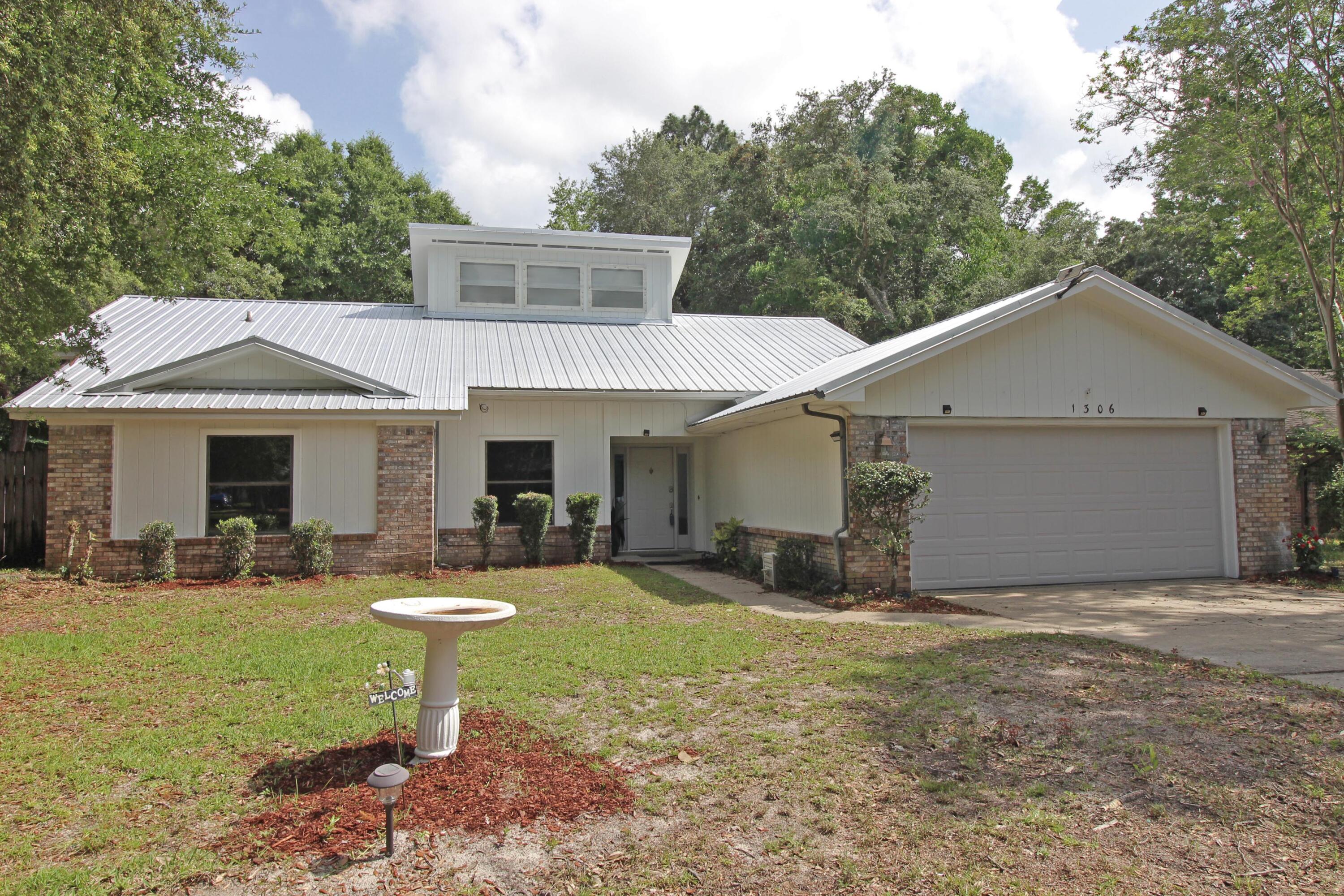 Welcome to this single-family home nestled in the Woodlands of Bluewater Bay at 1306 Rosewood Way in Niceville, FL. Spanning 2,139 square feet, this one-story residence offers a harmonious blend of comfort and traditional design. Step inside to discover a spacious layout featuring three well-appointed bedrooms and two full bathrooms, with double sink vanities and separate bathing areas. enhancing the bath's functionality. The home boasts an array of finishes, including hardwood, laminate, and tile flooring throughout. The abundant natural light through the large, encased windows in the living room is complemented by recessed lighting creating a warm ambiance through the home. The Kitchen is a culinary delight equipped with a breakfast bar overlooking the kitchen nook, granite countertops, and stainless-steel appliances. Entertain with ease in the formal dining room or relax by the fireplace in the inviting living room or enjoy the heated and cooled Florida Room at the back of the house with access to the Master bedroom. The outdoor space is large enough for a future pool. Fenced back yard with double gates on each side. The gazebo abutting the open patio is perfect for gatherings. Store lawn equipment in the metal storage shed. Complete with a lawn pump and sprinkler system for easy irrigation. Metal Roof and HVAC System installed 2020, casement and dual pane windows, electric heat, and a practical laundry room just off the kitchen will convey with a washing machine. The attached garage offers ample parking and storage workshop space, ensuring all your needs are met. Experience the perfect blend of style and convenience in this remarkable home. The exterior is newly painted. SOLD AS IS WHERE IS.