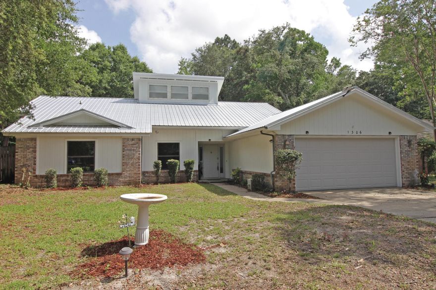 Welcome to this single-family home nestled in the Woodlands of Bluewater Bay at 1306 Rosewood Way in Niceville, FL. Spanning 2,139 square feet, this one-story residence offers a harmonious blend of comfort and traditional design. Step inside to discover a spacious layout featuring three well-appointed bedrooms and two full bathrooms, with double sink vanities and separate bathing areas. enhancing the bath's functionality. The home boasts an array of finishes, including hardwood, laminate, and tile flooring throughout. The abundant natural light through the large, encased windows in the living room is complemented by recessed lighting creating a warm ambiance through the home. The Kitchen is a culinary delight equipped with a breakfast bar overlooking the kitchen nook, granite countertops, and stainless-steel appliances. Entertain with ease in the formal dining room or relax by the fireplace in the inviting living room or enjoy the heated and cooled Florida Room at the back of the house with access to the Master bedroom. The outdoor space is large enough for a future pool. Fenced back yard with double gates on each side. The gazebo abutting the open patio is perfect for gatherings. Store lawn equipment in the metal storage shed.  Complete with a lawn pump and sprinkler system for easy irrigation.  Metal Roof and HVAC System installed 2020, casement and dual pane windows, electric heat, and a practical laundry room just off the kitchen will convey with a washing machine. The attached garage offers ample parking and storage workshop space, ensuring all your needs are met. Experience the perfect blend of style and convenience in this remarkable home. The exterior is newly painted. SOLD AS IS WHERE IS.