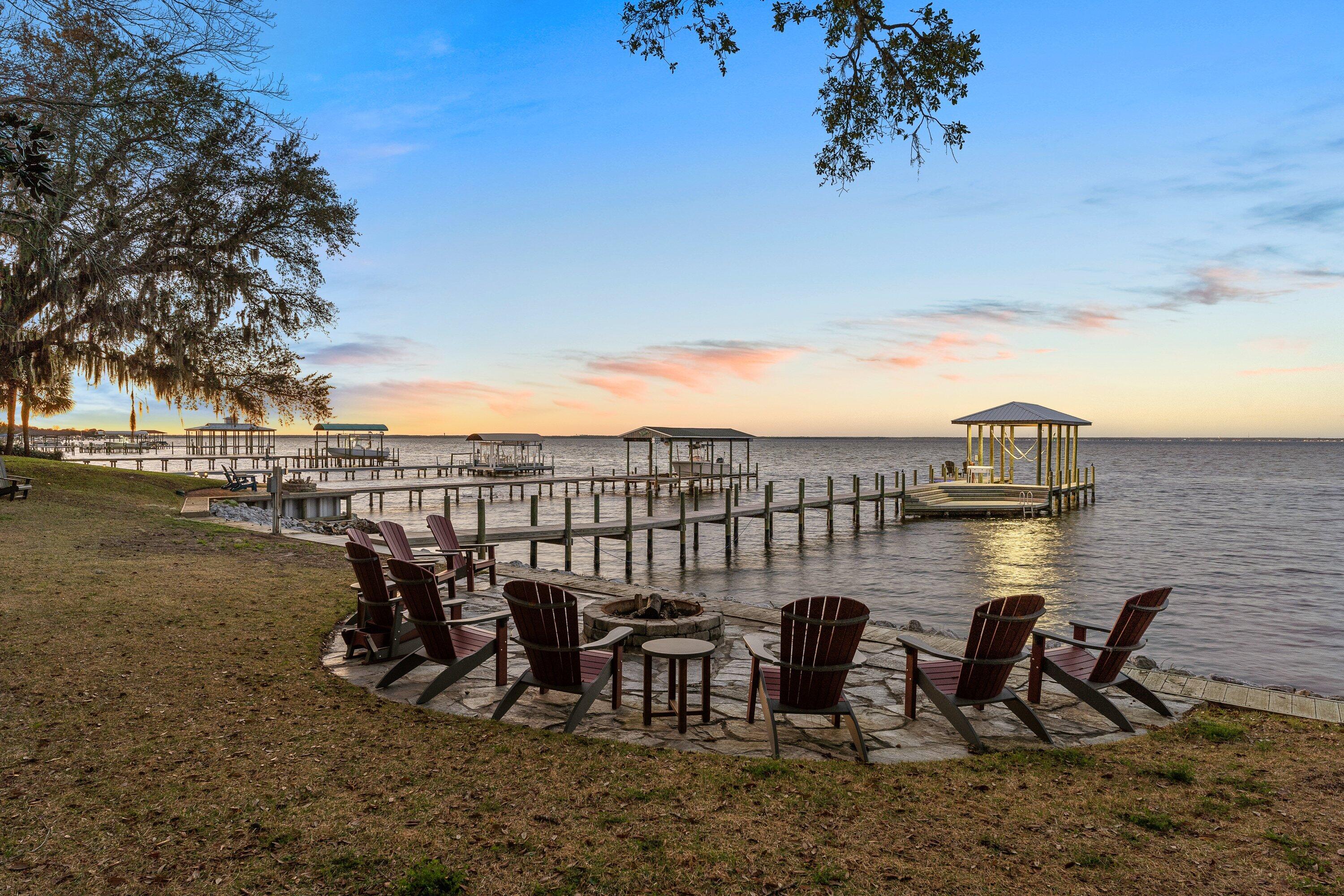 On a rare double lot with 200 feet of bay frontage, this fully updated brick estate is positioned down a gated, circular driveway between a canopy of mature oak, magnolia, citrus trees, and crepe myrtles. Built for entertaining, the expansive backyard is perfectly framed with stately live oaks surrounding a deep saltwater pool and oversized hot tub. Take in picturesque, year-round pool to bay views from several rooms in the house. Enter the foyer to an elegant curved staircase, where the well-thought out floor plan and thoughtful updates promote easy living and ultimate privacy.