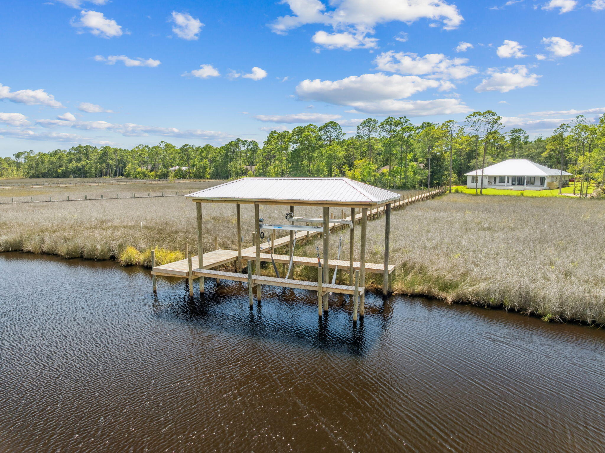 Welcome home to waterfront living on Eden Drive. This brand new, custom single-story home is situated on a private, half acre lot, including 4 bedrooms, 4.5 baths, a 3-car gar-age, boat dock and slip, and every amenity a family could desire. Delight in panoramic bayou views as you enter the home into a recessed foyer, the perfect space to feature artwork and welcome guests into your home. Designed with timeless finishes and thoughtful details, this residence features saddle brown stained oak floors throughout. The open concept living room boasts cypress accent coffered ceilings, a gas fireplace, and wet bar with wine and beverage center, creating the ideal entertainment space. Your stunning view is uninterrupted as you continue into the kitchen, showcasing an expansive Taj Mahal granite waterfall island with porcelain apron sink and antique gold bridge faucet. Preparing meals in this kitchen won't be a chore with a Butler's Pantry, Cafe 6-burner gas stove and double refrigerator/freezer. Just adjacent to the kitchen is a dedicated office space and additional storage with built-in desk and shelving. Step through full glass sliding doors to an expansive outdoor retreat. Enjoy your summer days and nights in your own backyard -- complete with covered patio, gas fireplace, outdoor kitchen, pool with sun-deck and hot tub, firepit, and a private dock and boathouse. With direct access to the In-tracoastal waterway and Choctawhatchee Bay, whether you plan to boat to dinner at The Bay or North Beach, or explore further to Destin Harbor and Crab Island, your boating options are endless right from your dock. The waterside master suite includes his and her closets, a soaking tub, and double shower for spa-like comfort. The three additional bedrooms offer ensuite bathrooms with custom tile finishes. The exterior of the home fea-tures artisan board siding, stucco accents, full glass steel front doors, and gas lanterns, portraying elevated Southern charm with modern luxury in Point Washington.