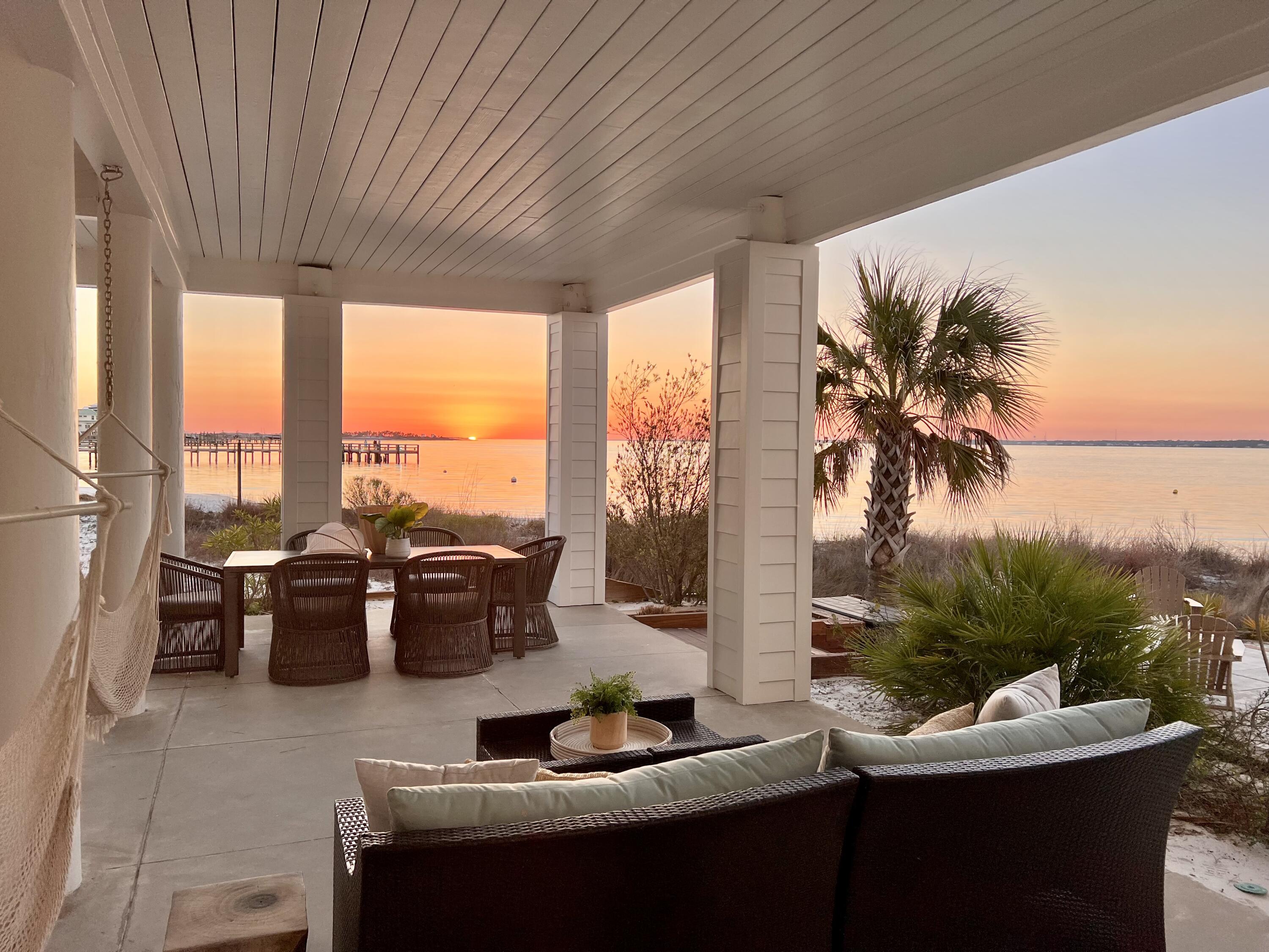 Discover luxurious island living in this beautiful waterfront home on Navarre Beach, perfectly situated on a white sandy beach with breathtaking water views of Santa Rosa Sound from every window. Nestled in the quaint, gated 'By the Sea' community, this professionally interior-designed, fully furnished luxury beach house offers the ideal retreat or smart rental investment.This customized home features two oversized ensuite bedrooms, each with a private balcony, along with two large guest rooms and two versatile bonus rooms--perfect for a variety of needs including additional sleeping space.The ground level includes an approximate 600 sf of gorgeously finished, air conditioned space with a full bath, creating the possibility of use as a 5th ensuite bedroom or added living area. Step outside to your back patio, surrounded by exotic palm trees and tropical plants, where you can enjoy a crackling fire pit and entertaining guests. The home provides direct access to the Sound side beach and water activities, including sailing, jet skiing, paddleboarding, fishing - all right outside your back door.
This home was beautifullly remodeled in 2023-2024. Upgrades include: new high efficiency Bryan AC systems with REME Halo purifier and auto cleaning; 2 car garages added/ enclosed with 210 car charger; New decking on front porch to add dry deck of garage, and new/ improved railings; Ground level air conditioned room/ bathroom; Full paint inside and out; All floors and tile surrounds replaced; Backsplash installed in kitchen and primary bath; Total kitchen remodel with enlarged island, added upper cabinets with new drawers and fronts, new countertops; All lighting and fixtures in home replaced; All new furnishings and interior design; Additional bathroom on second living level.
Enjoy the community's amenities, including a sparkling pool, deeded beach access to the Santa Rosa Sound, and a friendly atmosphere. Year-round sunsets create a truly magical setting, making this residence perfect for large family reunions or a peaceful retreat. With easy access to the Gulf of Mexico (just a five-minute walk), this charming, quaint community offers an unparalleled coastal lifestyle.