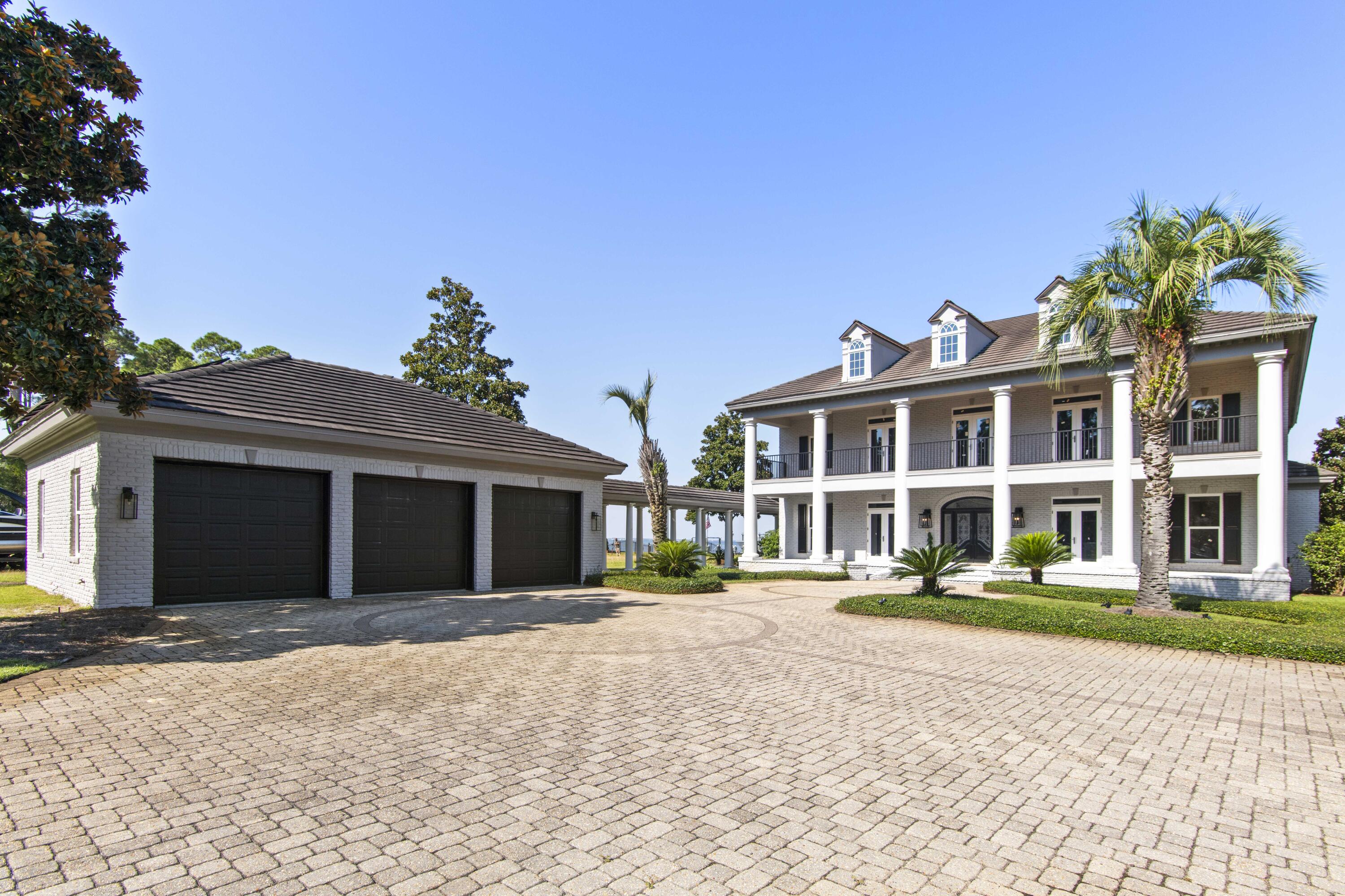Experience luxury living on nearly an acre of prime bayfront property. This stunning estate features all new windows and doors, fresh interior and exterior paint, and a beautifully renovated kitchen designed for both style and function.Inside, a grand foyer opens to formal living and dining spaces, complemented by gleaming hardwood floors, a butler's pantry, and thoughtful details throughout. The home also boasts a private theater, spacious living areas, and double covered porches with sweeping water views.Outdoors, enjoy resort-style amenities including a sparkling pool with expansive patio, outdoor kitchen and bar, and a private dock with boat lift--perfect for embracing the coastal lifestyle.The gated drive leads to lush landscaped grounds with citrus trees and palms, plu