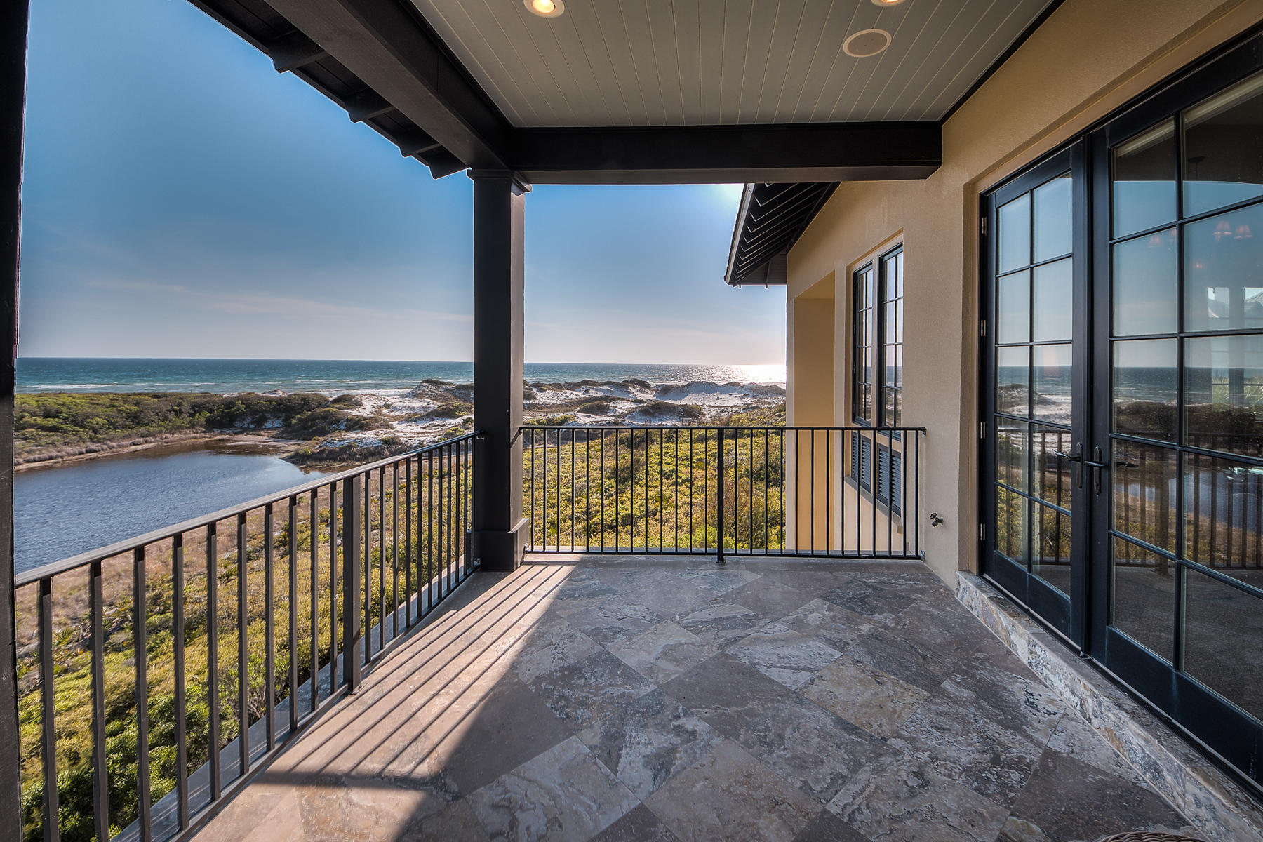 Overlooking a rare coastal dune lake with spectacular views of the Gulf of Mexico, this concrete-constructed legacy home was designed by renowned architect Dawn Thurber, Thurber Architects. Almost every room in this noble structure overlooks a layered vista of sugary dunes, sparkling lake and blue-green gulf. The generous pool deck, featuring a heated pool and hot tub, and multiple verandas offer respite for sun and shade lovers alike. The outdoor breezeway includes a wood-burning fireplace with gas logs and a Viking grill.A wood-paneled elevator services all three levels of this traditionally appointed home. Arched doorways, paneled doors, a three-story, wrought iron stair railing and stone floors create an authentic Old World, European-style atmosphere.