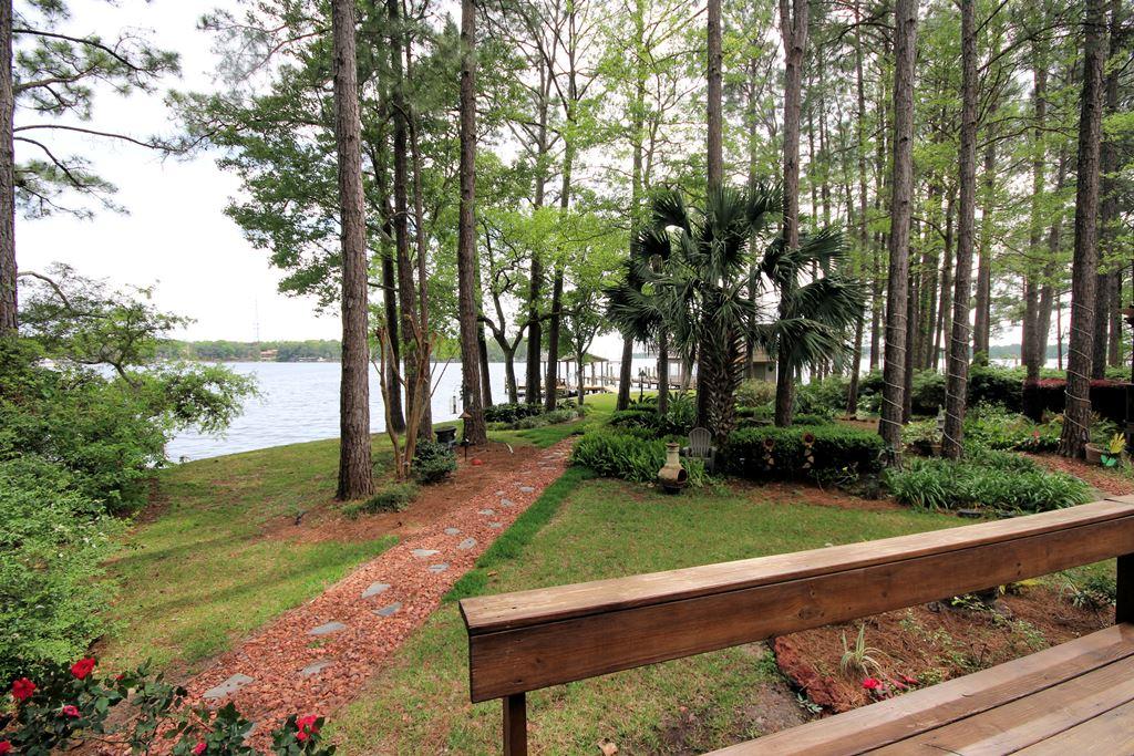 INCREDIBLE home on almost an acre of tree studded property with 150' on gorgeous Rocky Bayou offering incredible views! When you enter this property through the stately brick entrance, you traverse along the circular paver driveway until you get to the home nestled sedately in the trees. Upon entering this home, you will be impressed with the stunning curved open staircase that graces the foyer. Alongside the foyer is the music room that can also be used as a formal dining room. Straight ahead is the family room with a dramatic vaulted ceiling accented by a travertine fireplace but your gaze will be drawn to the large impact glass windows that look out over the lush back yard and bayou beyond. The family room is open to the nicely updated kitchen with stainless appliances, beautiful