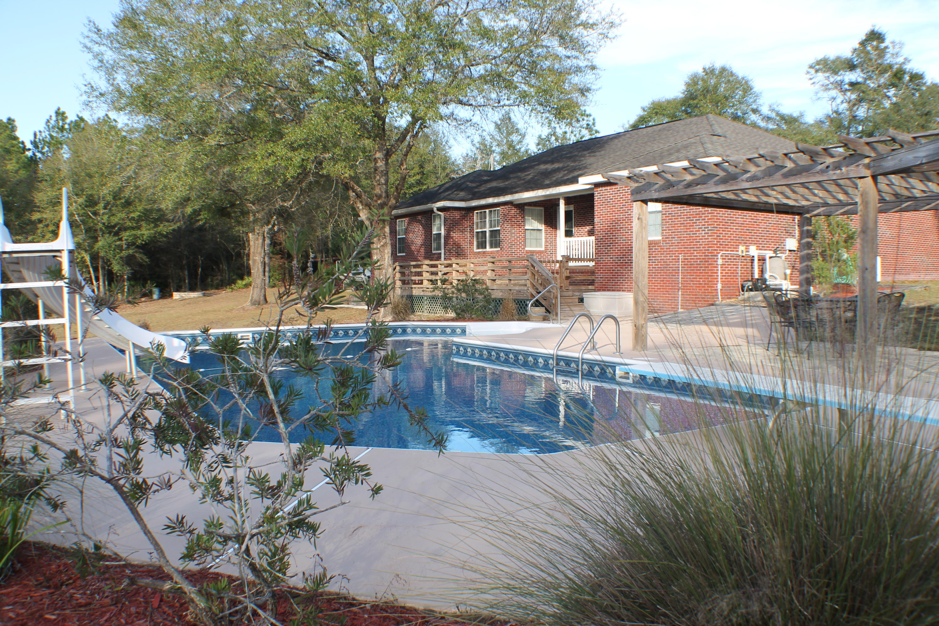 Location South if I-10 ! No covenants on 6 acres with a pool, a barn , a porch , shooting range and a dog pen! Pull up the circular drive to this all brick 3 bedroom 2 1/2 bath home. 2 car carport with room to grill ! Ladies step inside for an elegant home with all the upgrades! The corner fireplace in the large living room will keep you warm on cold winter nights! Tile and laminate floors through out . Stainless steel appliances. This kitchen has a pantry and is situated between the formal dining room and the breakfast room. The split floor plan has two large rooms and a hall bath on one side and a large masters quarters on the other! Custom master bath with double vanity sinks, a jacuzzi tub, separate shower and large walk in closet. Just off of the living room is a large office