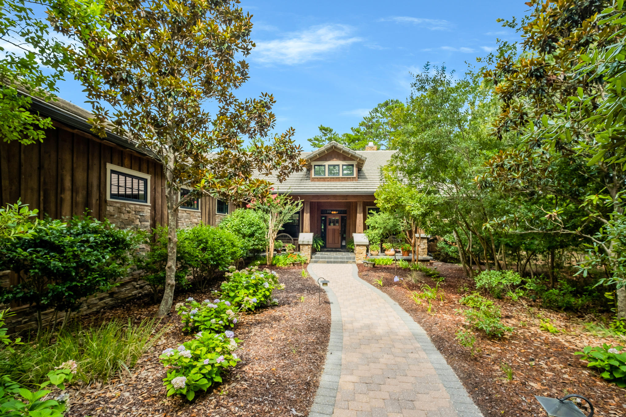 It's rare to find a quality custom-built home close to 30A in a peaceful community on a coastal dune lake with golf, but this craftsman home ticks all the boxes. Located on one of the larger lots in the gated community of Wild Heron, this secluded home boasts a sweeping brick paved driveway canopied by beautiful trees and a 3-car garage with ample coveted storage. Reflecting its unspoiled surroundings, this home makes extensive use of natural materials. Check out the imposing mahogany front door, stacked stone columns, cedar siding, wood-clad windows, concrete roof, slate tile and rich Brazilian hardwood floors. Well maintained, this bespoke home has custom kitchen cabinets, granite counters and a bevy of stainless Kitchen Aid appliances including