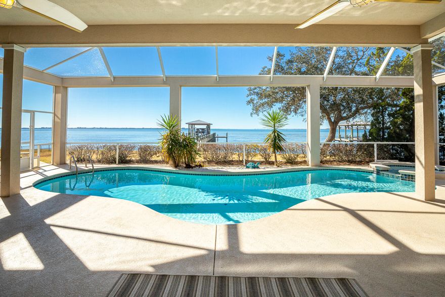 Accepting backup offers! A beautiful bayfront setting in the gated Southwind community of Bluewater Bay offers year-round sunset views from almost every room. Experience the timeless features of this custom home with thoughtful upgrades and impactful finishes. Find 9-12 foot ceilings and an open floor plan to highlight the three sets of glass doors which open to the screened-in pool, spa, and fountain, and the bay beyond. A remodeled gourmet kitchen includes a gas cooktop, wine cooler and ice maker. Enjoy coffee from a built-in banquette in the kitchen as you watch dolphins play in the distance. New flooring throughout. The master bedroom offers pool and bay views, while the master bathroom features separate vanities, a walk-in shower and soaking tub. Entertain year-round on the back patio