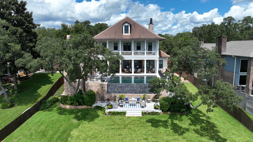 This stunning waterfront home is an architectural masterpiece! From the second you drive up the quality and details are impossible to overlook. Stepping into the beautiful plantation-style brick home you're immediately met with a warm character from features including incredible wide plank reclaimed heart pine flooring, wood beams, a gas fireplace with surrounding built-ins, and a wrought iron staircase. A wall of doors and windows allows for breathtaking views of the infinity pool and waterfront. The gourmet kitchen is top-of-the-line with Thermador appliances, a sub-zero ice maker, and beverage cooler, custom cabinets with glass fronts, beautiful granite countertops, and a large center island with a breakfast bar.