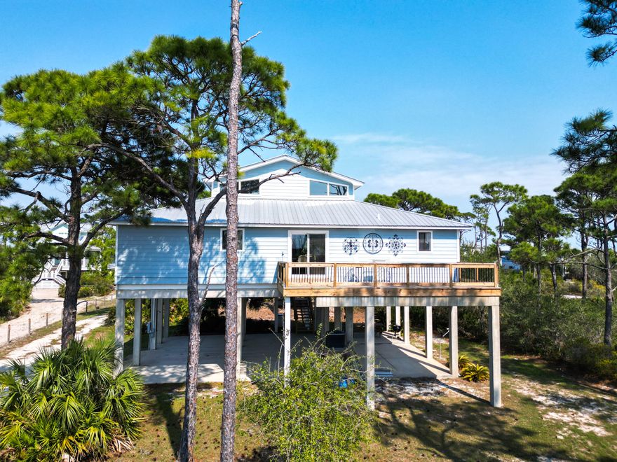 Coastal Comfort Meets Scenic Bayside Living; Welcome to your slice of paradise on St. Joseph Bay, perfectly situated in the sought-after Cape San Blas area. This charming first-tier, single-level home offers 2 bedrooms and 2 bathrooms, blending relaxed coastal style with modern comforts, all just steps from the water's edge. Designed for easy living, the open floor plan brings together the living, dining, and kitchen spaces in a bright, airy setting filled with natural light and picturesque water views. The kitchen is both stylish and functional, featuring granite countertops, custom cabinetry, a deep stainless steel sink, and high-end appliances, ideal for everything from casual breakfasts to evening gatherings. The spacious primary suite provides a peaceful retreat with a king bed, dual vanities, and a walk-in shower. The second bedroom is equally inviting, offering flexible sleeping arrangements and direct access to the outdoor deck. Both bedrooms feature sliding glass doors that open to expansive outdoor living spaces, enhancing the connection to the coastal surroundings. Step outside and unwind on the screened porch or stretch out on the large deck, perfect for dining al fresco, enjoying the sea breeze, or watching the colors of the sunset fade over the horizon. Multiple outdoor access points, including a Gulf-facing deck off the dining area, give you plenty of options to take in the views. A dedicated and shared dock adds to the appeal, making it easy to enjoy boating, fishing, or simply soaking in the beauty of St. Joseph Bay. This home has great beach access options and is located equidistant about 2000 feet from Cape Palms Park (Gulf County) or William J Rish State Park. Whether you're looking for a private coastal escape or a property with strong rental potential, this Cape San Blas retreat offers the best of both worlds. Added Value Opportunity: An additional vested and approved roadside lot is available for purchase, (see MLS listing 999392)