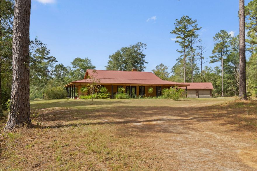 Slice of Paradise in North Florida!!! If you're looking for that country home and plenty of room to roam, then look no further! Charming log cabin home on 243 +/- acres with a lake and a clear sandy bottom creek running across the property. Home is tastefully appointed with plenty of wood work - modern kitchen with granite tops - expansive living and dining areas with vaulted ceilings - split bedroom design and a wonderful porch for enjoying the fabulous views. Additional features include a large metal barn - 2 stall horse barn with tack room - garage/workshop and lean to for the tractor and toys -  and a ready made arbor. Wildlife galore on over 240 acres that features a mix of mature and various age pines as well as hardwoods. Roads/trails running throughout the parcels. Plenty of possibilities to put your personal touch on this slice of paradise in beautiful Laurel Hill, Florida!