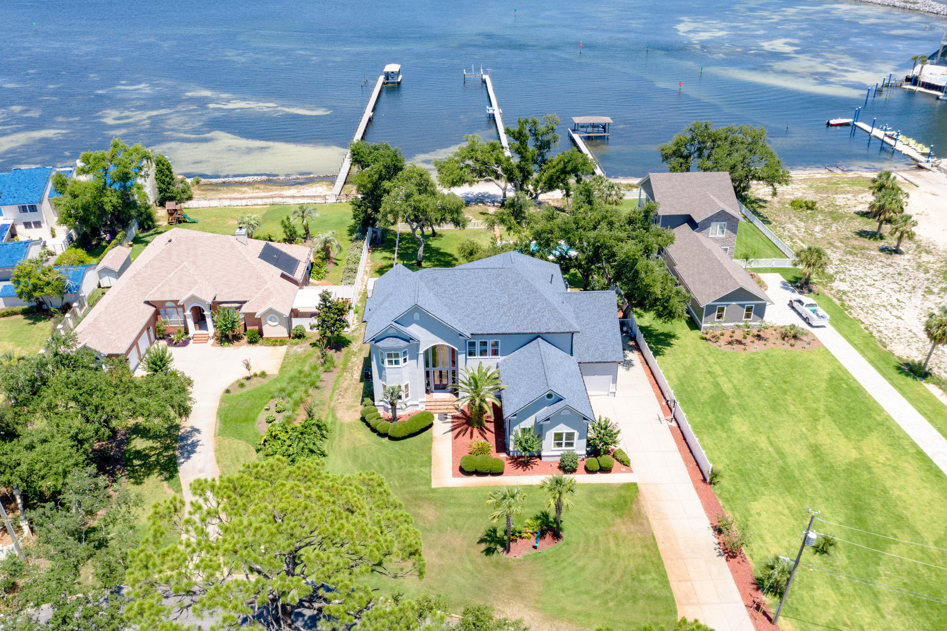 TAKING BACK-UP OFFERS ---Stunning views await you from this one-of-a-kind, custom bay front home sitting on nearly a full acre in unincorporated Panama City Beach.  The 300' pier with 30,000 lb boat lift is the perfect place to park your yacht/boat.  Want your own private beach?  Look no further, 110 ft of private beach awaits you.  Entering this magnificent home, you'll immediately feel captivated by the 30'ft ceilings and Italian Crystal Chandelier.   Your eyes will then be drawn to the sprawling lawn, mature oaks and endless water views. First floor features hard wood and tile flooring, spacious guest bedroom, full bath, living room, library/den (with marble fireplace), kitchen and dining area. The chef in the family will appreciate the updated bisque cabinets,