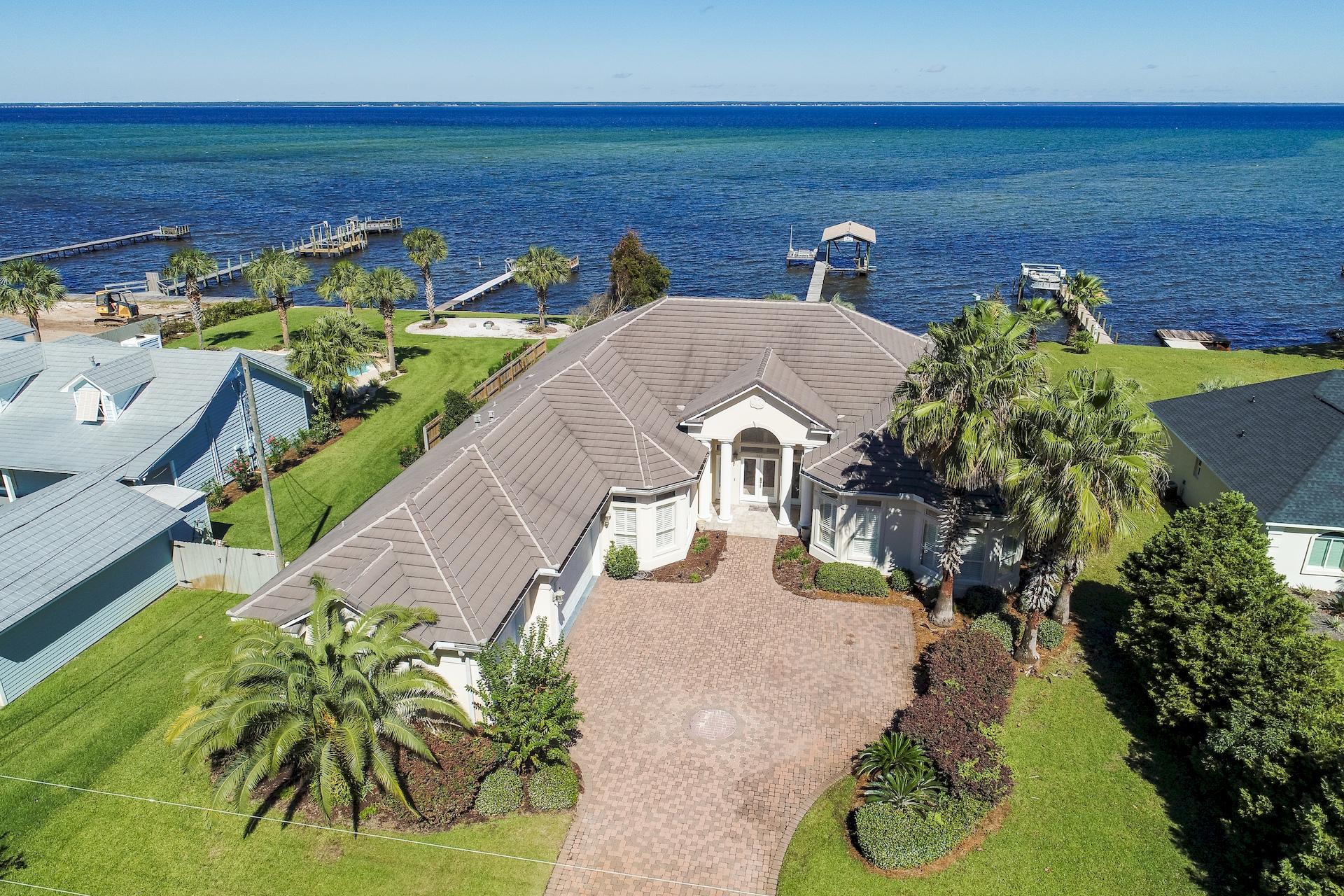 Enjoy coastal living in a serene tropical setting with this Bay front estate in Miramar Beach! No HOA fees and expansive lot over 1/2 an acre (0.53) is a rare treat. With 100 feet of water frontage on the Bay, you have your own private oasis! Home is complete with dock, boathouse with slip, sun deck, incredible screened-in pool, hot tub and covered lanai. Outdoor living and huge backyard with tropical landscaping sets this home apart from the rest. Ideally the home is one-level with beautiful architectural details like trayed ceilings, stunning archways & columns on the interior, thick crown molding & great natural light. The interior has just been repainted for a fresh look along with brand new carpet. There are 4-bedrooms including a Bay front master, additional office and 3-car garage.