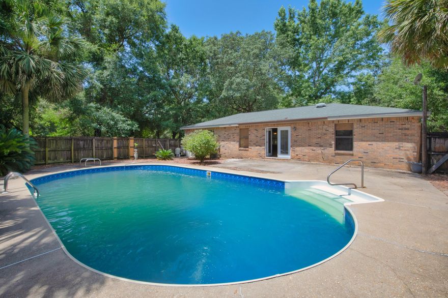Dive into paradise in this lovely pool home displaying a picturesque setting and placed upon a large lot that is engulfed by lush overhanging trees. This brick ranch is perfectly framed with a large circular driveway, abundant foliage, stone detailing with coordinating shutters, and a remote landscape that lets you enjoy the best of both worlds. As you approach the entrance, you are greeted by a charming front porch that is perfect to enjoy your morning coffee and finished with a beautiful mahogany and glass paneled door that leads you to the foyer. The main living area flows wonderfully consisting of an open floorplan where you can enjoy views of every room, easy entertaining, and tile throughout. The attractive kitchen features plenty of cabinetry, a picture window over the sink,