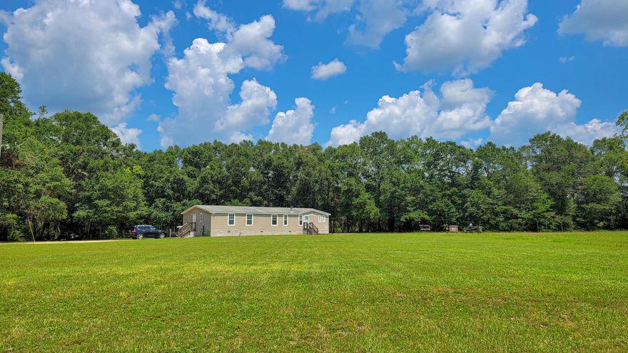 Back on Market! Buyer financing fell through. Country living without the drive! Time to relax at this private 4 bedroom 3 full bath home in Holt. As you drive down the unpaved road, you'll appreciate the seclusion and the location of the property. As you head up the front porch steps and step into the home, you'll be welcomed into a spacious open floor plan! The formal living space has a beautiful wood-burning fireplace and leads you through the dining area / kitchen. The kitchen has plenty of storage for your home chef, an island for additional prep space, and a breakfast bar for seating. Other features include a unique custom-built hanging pot rack. Past the kitchen is another large family room with natural light and tray ceiling.