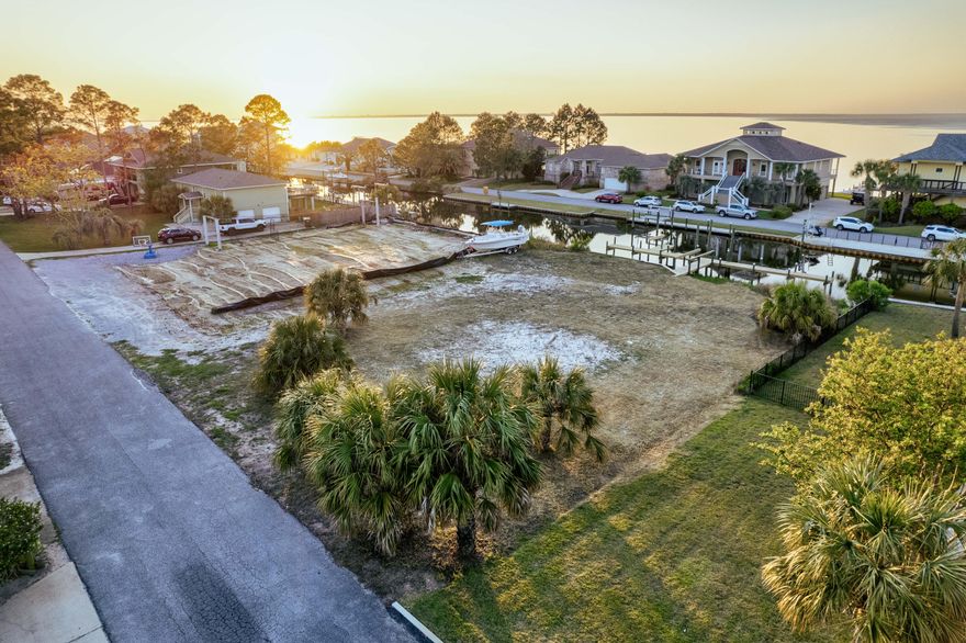 Right on the beautiful, deep water canal in Whisper Bay, this waterfront lot immerses you with stunning views of the Pensacola Bay. Build your dream house on the 0.26 acre lot, with 100 feet of water frontage! Both the boat dock and the retainage wall were refurbished in 2024, making this lot build-on ready! The house foot print on this property is 3500 sq. ft. leaving plenty of room for a pool, hot tub, or backyard of your dreams. The lot has been cleared and has some wetlands, but mitigation with the Corps and D.E.P. has been completed (documents on file). Here, you will have about 6 feet of depth in the canal from the boat launch, making for conveniently smooth access to the Bay. All utilities are in the road (no taps have been paid). Don't wait on turning your property dreams into a reality!