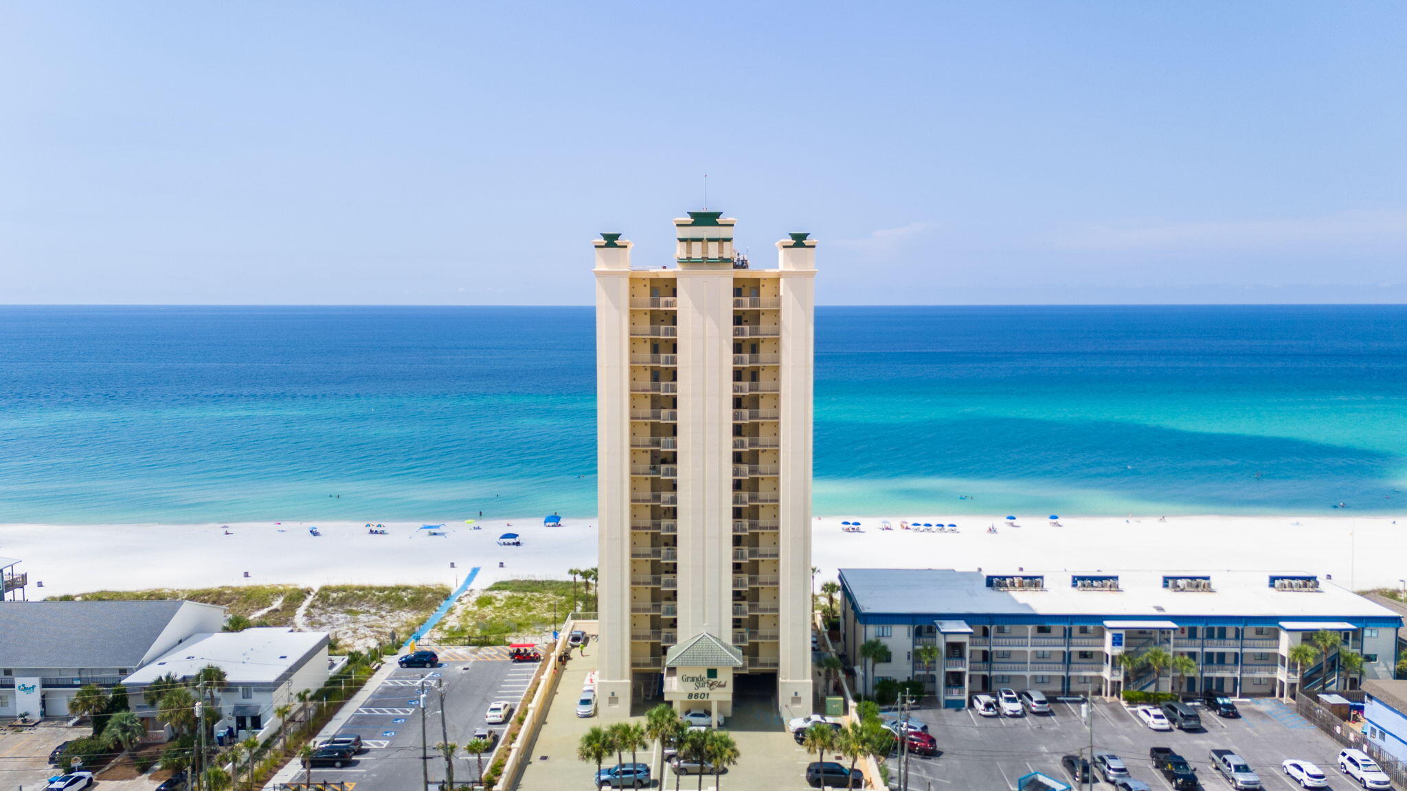 Experience luxury living at its finest in this exclusive top-floor high-rise condo, located in a private gated community off Thomas Drive. With only 2 units per floor and 28 total, enjoy ultimate privacy and serenity. This 3-bedroom, 2-bath condo includes two deeded parking spots--one covered and directly beneath the building. Take in breathtaking sunsets from the oversized west-facing balcony, perfect for relaxing or entertaining. Just steps away from the upcoming Tootsies Orchid Lounge and Margaritaville Hotel, this location offers both peace and excitement. Featuring a spacious kitchen and open layout, this condo is ideal as a vacation rental or private retreat. Don't miss this rare opportunity to own a piece of paradise.