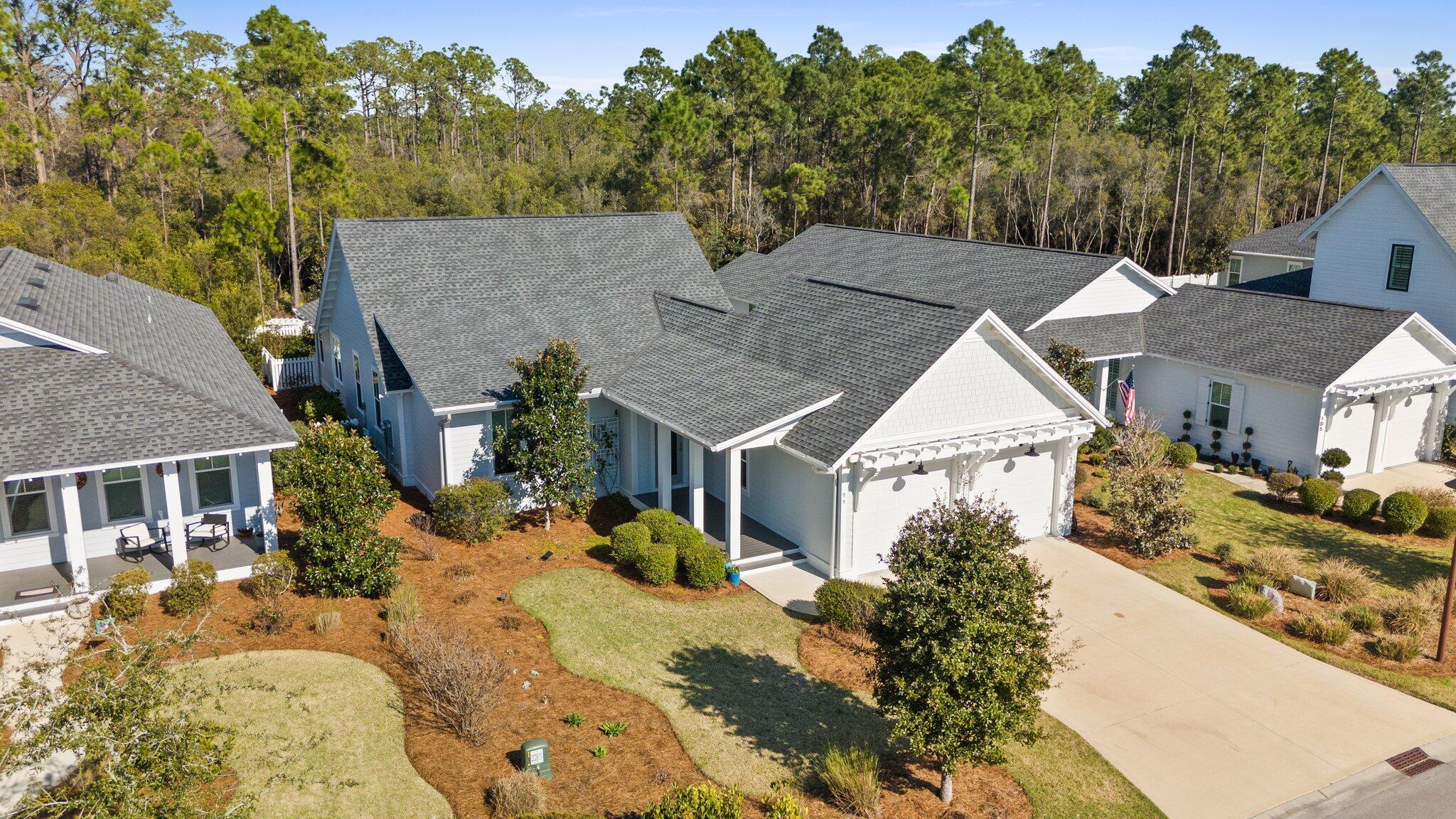 Stunning, move-in ready home on a peaceful premium lot priced at a discount to new construction! Welcome to 95 Log Landing, a meticulously kept 3 BR, 3 BA home on one of the rare large lots in Watersound Origins encompassed by nature, with a beautiful open park across the street and a serene, protected wooded-preserve in back. This stunning residence is designed for those who appreciate quality, comfort, style and tranquility with nature. As you step inside, you'll immediately be greeted by abundant windows offering generous natural light and beautiful nature views in back, warm wide plank, oak engineered-wood flooring, and a calming palette throughout. The open-concept design allows for effortless flow between the living, dining, and kitchen areas. The gourmet kitchen offers warm cabinetry, premium appliances, a stylish lit dry bar, beautiful quartz countertops, an elegant custom, silicone-granite sink, and large walk-in pantry. Additionally, the home features an upgraded HVAC system offering greater energy efficiency, humidity reduction, UV lights and a Solaris whole home air-purifier system ensuring healthy air quality and improved air flow for a comfortable living environment.
The large screened rear porch includes an oversized, comfortable swing bed to enjoy the beautiful fenced backyard, extensively landscaped for privacy and backing to a peaceful wooded preserve. The home features offered by this Huff Homes' modified Begonia plan include attractive curb appeal with its high-elevation roofline, a 2' wider garage, and owner installed whole-home steel gutter system. Three premium Smart LED TVs and a high-quality Murphy bed are included with this luxurious, comfortable home in close proximity to gorgeous beaches and wonderful area amenities. Enjoy all the offerings of this master planned community including a resort-style pool, top of the line fitness center, tennis, pickleball, volleyball, basketball, playground and UNLIMITED GOLF on an award winning course! The new Town Center, conveniently located at the front of the neighborhood, is designed to serve the community offering a Publix, Starbucks, restaurants, shops, medical facilities and event spaces! Don't miss out on the chance to make this incredible home your own!