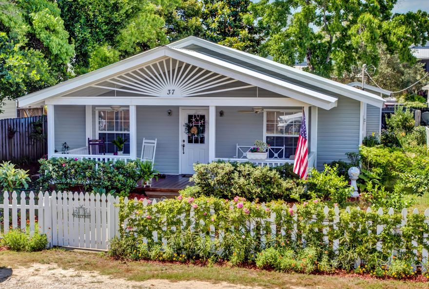 This precious cottage by the sea offers a simple, low-stress lifestyle and plenty of charm! The one-story home is surrounded by several fruit trees and a bountiful flower garden, which can be enjoyed while relaxing on the wide front porch. The interior features an open-concept living room/dining room/kitchen with gorgeous heart pine floors and a vaulted ceiling. Beautiful black granite countertops and an island with breakfast bar enhance the kitchen.The spacious master bedroom enjoys an ensuite bath with converted shower and beadboard details. An additional bath can be accessed from the main room or the second bedroom. Currently used as an office, the third room would also make a great bunkroom, especially if the property is used as an income-producing rental.The backyard includes.