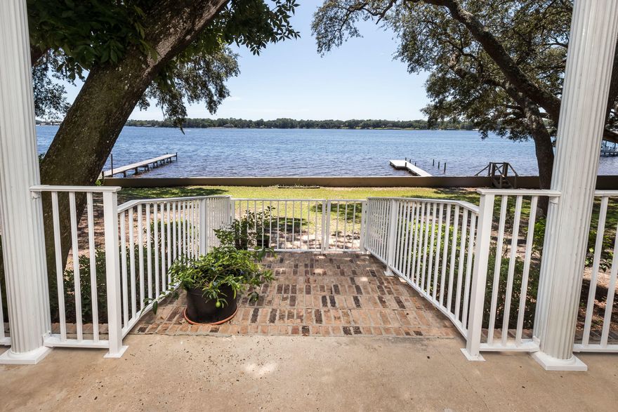 Western facing waterfront home on gorgeous Boggy Bayou with amazing sunset views on a stunning .74 acre lot. Because of the high elevation, the lot is not in a flood zone and the 128' of shoreline is protected by both a seawall AND a steel reinforced concrete retaining wall! The lot is studded with beautiful old growth oak trees and there is plenty of room for a future pool. The custom built, one owner all brick home has been well loved and maintained and the flexible floorplan will fit almost any buyers needs. There are TWO master suites in the home, one downstairs and one upstairs as well as TWO additional bedrooms and TWO living areas. When you drive up to this home, you will immediately notice the stately columns that grace the front of the home. When entering through the front door,