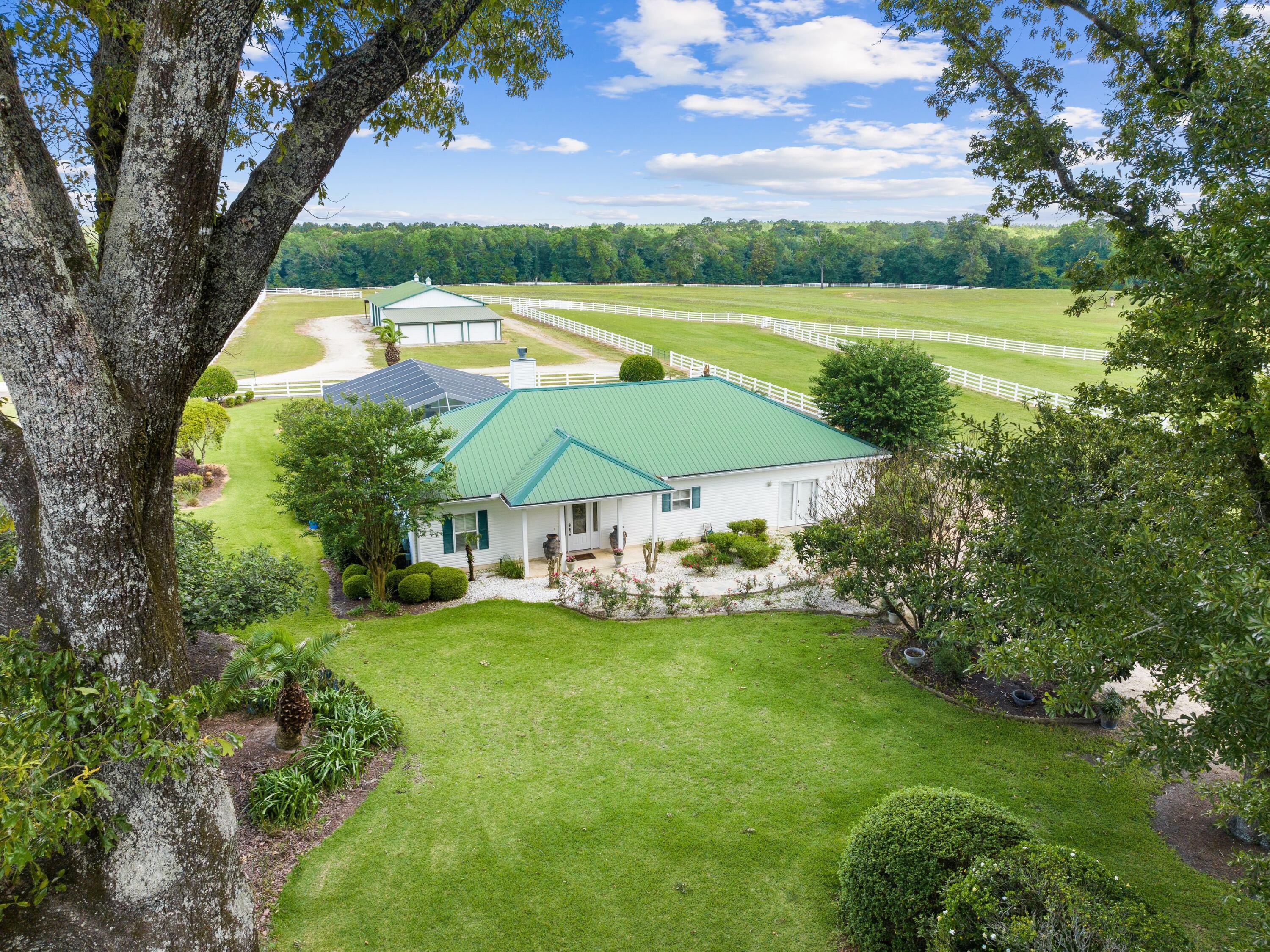 Horse lovers and equine professionals will covet this working ranch that rivals any facilities elsewhere. It boasts a world-class equestrian facility, purposely designed for training, boarding and breeding horses, or perhaps for enjoying as a private retreat for the new owner and horses. The pristine 42-acre property includes a beautiful home, three barns and several wells. It has seven fenced paddocks with prime Argentine Bahia grass and automated watering systems. Serious riders will appreciate the lighted outdoor riding arena with footing designed for performance horses. The 4,800-sq.-ft. modern horse barn can withstand winds up to 140 mph. It has twelve 14x14 stalls, each with its own center drain and individual high-performance ceiling fans, custom slip-resistant rubber mats that aid in cleanliness and fly control system. The air-conditioned tack room is equipped with a washer/dryer and refrigerator, and has hot and cold water and a half bath. The 4,840-sq.-ft. equipment/storage barn includes three oversized garage spaces and a workshop. The third barn is 6,850 square feet with concrete flooring, great for storage for hay, shavings and trailers. An industrial diesel generator and a high-pressure agricultural well ensure the ranch is totally self-sustaining. After a busy day, the well-appointed home offers a relaxing haven with three spacious beds, three baths and two large living areas, both with cozy feature fireplaces. Tile flooring provides a seamless flow into the open gourmet kitchen, which has granite countertops and a host of cabinets and appliances. The master suite is particularly spacious and has a lavishly appointed bathroom with a deep jetted tub, walk-in shower and twin vanities. When you could go for a dip in a pool, the huge screened patio has a kidney-shaped pool and a hot tub for soothing aching muscles. It's surrounded by far-reaching views of the surrounding paddocks and mature native trees. Combining a dream home and lifestyle with the possibility of a working equestrian business, this is a unique opportunity to change direction and secure the good life. Located close to I-10, this dream facility is convenient for many A-rated equestrian events as well as South Walton beaches and the Destin-Fort Walton Airport.