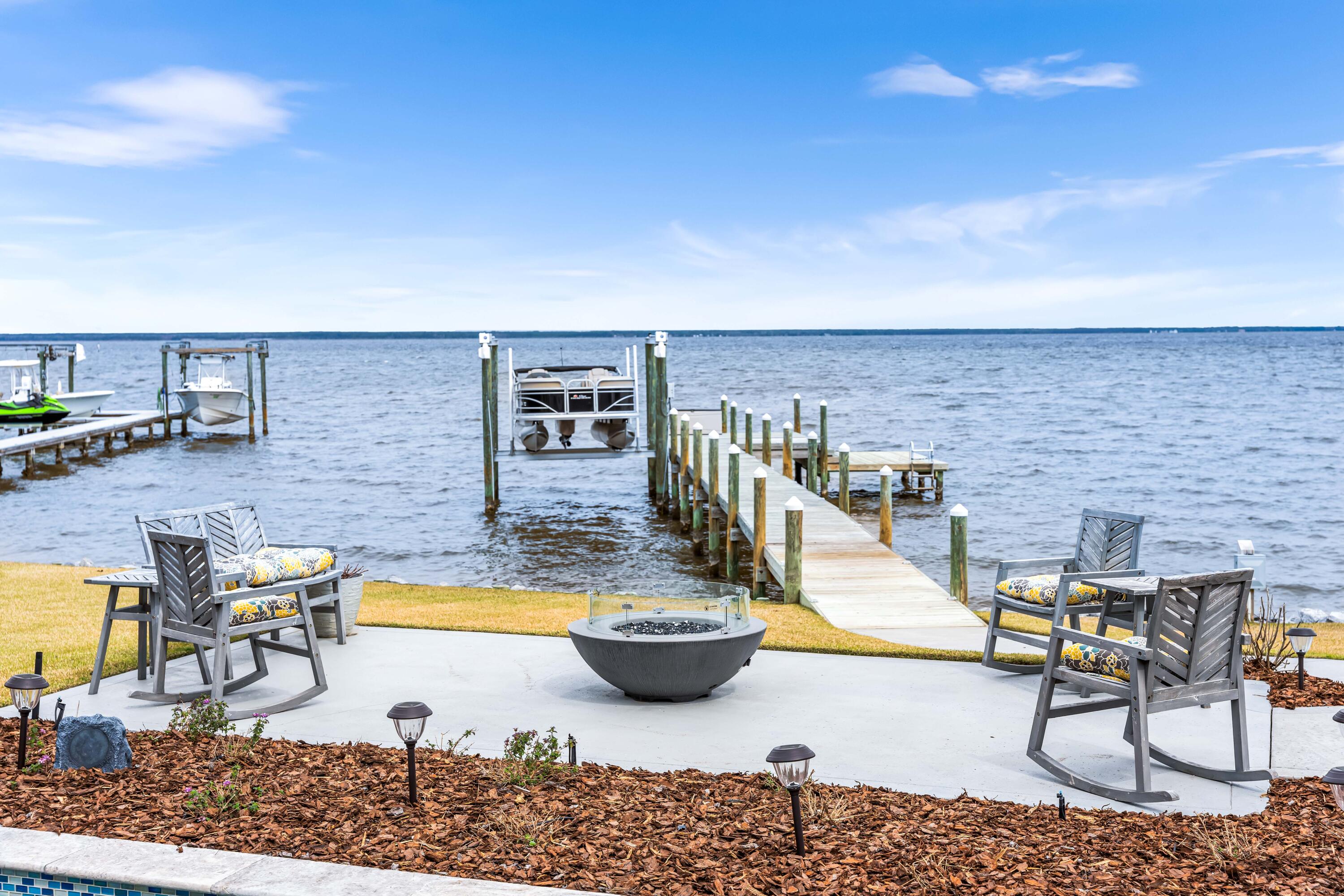Welcome to your dream retreat ON THE BAY! This exquisite custom design build by Romair Construction offers unparalleled luxury living, complete with its own private boat dock featuring a swim platform and 6,000 lb boat hoist. Step inside to discover an inviting open floor plan designed for effortless entertaining, highlighted by expansive windows that flood the space with natural light and showcase breathtaking views of the bay.Indulge in the comforts of a spacious primary en suite, featuring a luxurious tile shower, double vanity, and an expansive walk-in closet. Enjoy direct access to the incredible backyard oasis, where you can unwind and soak in the stunning sunsets.
