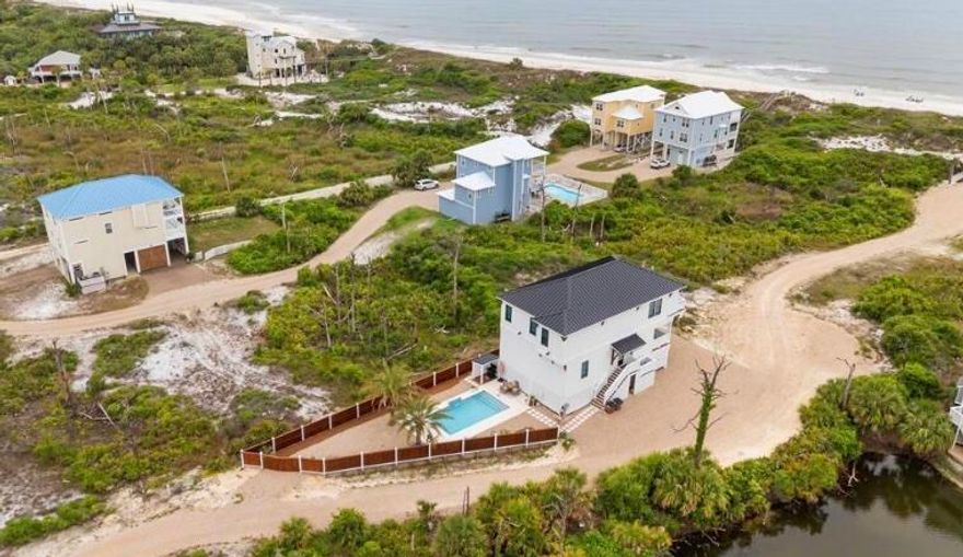 NO HOA! This stunning 2024 4-bed, 3.5-bath beach home is fully furnished with 2 large balconies. Kitchen has CAFE appliances, quartz countertops, range hood, pot filler, and soft close cabinets and drawers. Home has Vaulted Ceilings, a Wet Bar, and wide plank vinyl flooring. A convenient office study area with built-in cabinetry offers a workspace. The primary suite has trey ceilings, a spa-inspired bathroom with a frameless shower, floor-to-ceiling tiles, and bathtub. 2nd bedroom has a private bathroom, marble-tiled walk-in frameless shower, dual sinks, and a private balcony with stunning water views.  Enjoy resort-style living with a heated saltwater pool, a grill area, and a privacy fence. Whether you choose this gem as you residence, vacation home, or investment property, it's a WIN!