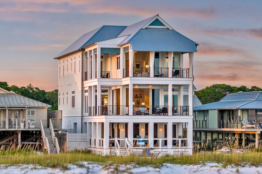 Boundless views and unforgettable beach days define this newly built gulf-front residence designed by Geoff Chick and completed in 2023. This architectural masterpiece rises along the shoreline, where walls of glass frame the ever-shifting colors of the Gulf of Mexico and Oyster Lake. Expansive balconies and a seamless indoor-outdoor flow create a living experience that feels both modern and timeless.The main level offers a soaring great room where sliding glass walls dissolve into the horizon, a gas fireplace anchors the space, and a quartzite-clad kitchen with a butler's pantry inspires culinary creativity. Gather around the oversized island or take meals to the covered gulf-front terrace where the water provides the backdrop. Beach-level living is equally impressive with a screened entertainment terrace featuring a fire pit, outdoor kitchen with vented grill, and Jacuzzi for sunset soaks. A powder room and outdoor shower add convenience, while private beach access ensures days begin and end in the sand.

Five ensuite bedrooms, including a bunk room, each open to balconies with gulf or lake views. A main-level suite provides accessibility, while the top-floor primary retreat boasts cathedral ceilings, a private furnished balcony, and an ensuite beverage bar for morning rituals. Dual laundry rooms, elevator service to all floors, and abundant storage ensure every need is met. 

Additional features include 12 foot ceilings on all floors, a Tesla EV charger, two-car garage, and a whole-house generator. This masterfully designed gulf-front residence offers an elevated coastal lifestyle, where design, comfort, and nature converge in perfect balance.

