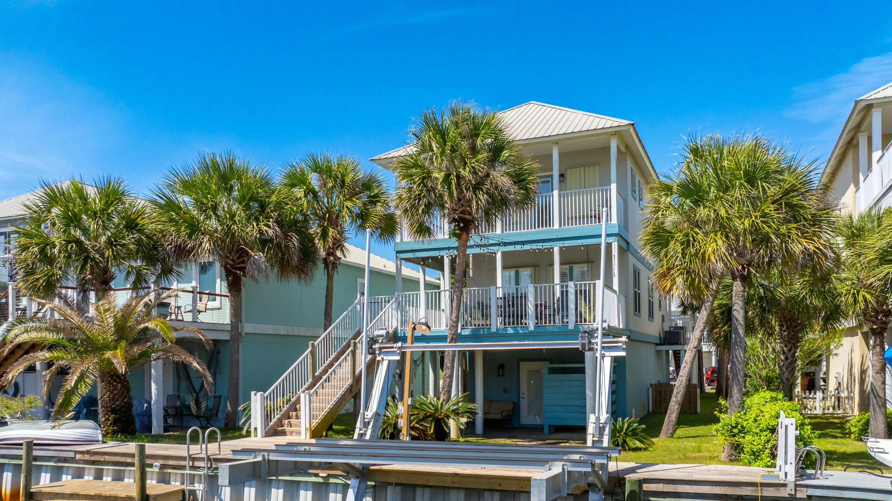 Welcome to Homeport!  A community that has access to all of your families favorite things about Navarre Beach!  This 4 bedroom, 3 bathroom Canal front home has a new boat lift installed in 2023, two double length garages, gorgeous outdoor living space and is just across the street from the community pool!  You can play all day in the sand, water or pool depending on what you're in the mood for!  With a fresh coat of paint inside and out, 1406 Homeport is ready for your summer plans!  This home is turnkey and being sold furnished with the exception of the twin beds in the downstairs bedroom.