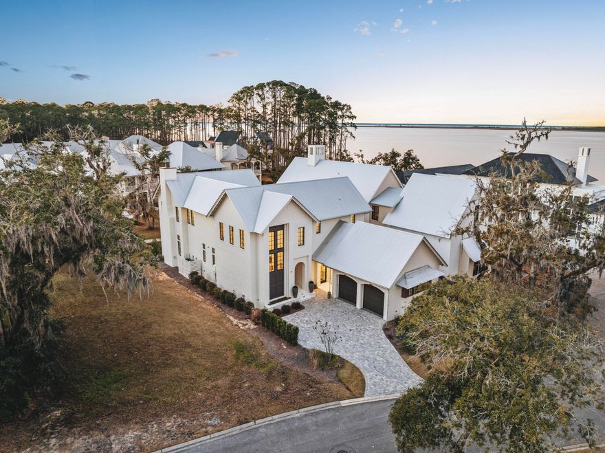 Set within the gates of Churchill Oaks, this thoughtfully designed residence captures peaceful bayou views and a level of craftsmanship rarely found. Architectural details such as arched doorways, a vaulted two-car garage, and decorative rain-chain downspouts establish the home's distinctive character, while light oak flooring, Restoration Hardware lighting, and a grand motorized foyer chandelier create a refined, welcoming interior.The well-conceived floor plan balances everyday functionality with elevated design, featuring a butler's pantry, boot room hallway, and a stylish guest bath with designer wallpaper. A first-floor junior suite offers comfort and privacy, complete with an elegant ensuite bath showcasing an oval soaking tub, dual vanities, and a frameless glass shower. At the center of the home, the open-concept kitchen is both striking and highly functional, appointed with floor-to-ceiling cabinetry, quartz countertops, a contrasting wood and white granite island, and premium Wolf and Sub-Zero appliances, including a six-burner gas range. The adjacent dining area with wet bar flows seamlessly into the living room, where wood-beam ceiling details and a gas fireplace create a warm yet sophisticated setting. Expansive sliding glass doors open to a spacious terrace designed for year-round enjoyment, complete with outdoor heating, electric screens, and a plunge pool with a tranquil water feature.
Accessible by private elevator, the second level includes two beautifully appointed guest suites and a vaulted primary suite designed as a true retreat. The spa-inspired bath features a frameless glass shower and a custom dressing room with extensive built-in storage, while a private screened porch offers sweeping views of Hogtown Bayou and the surrounding natural landscape.
Churchill Oaks is an exclusive 40-acre gated waterfront community with just 87 homesites, offering residents access to a deepwater marina, waterfront clubhouse, three resort-style pools, fitness center, and outdoor gathering spaces. The result is a lifestyle defined by privacy, natural beauty, and effortless access to boating and the best of the Emerald Coast.